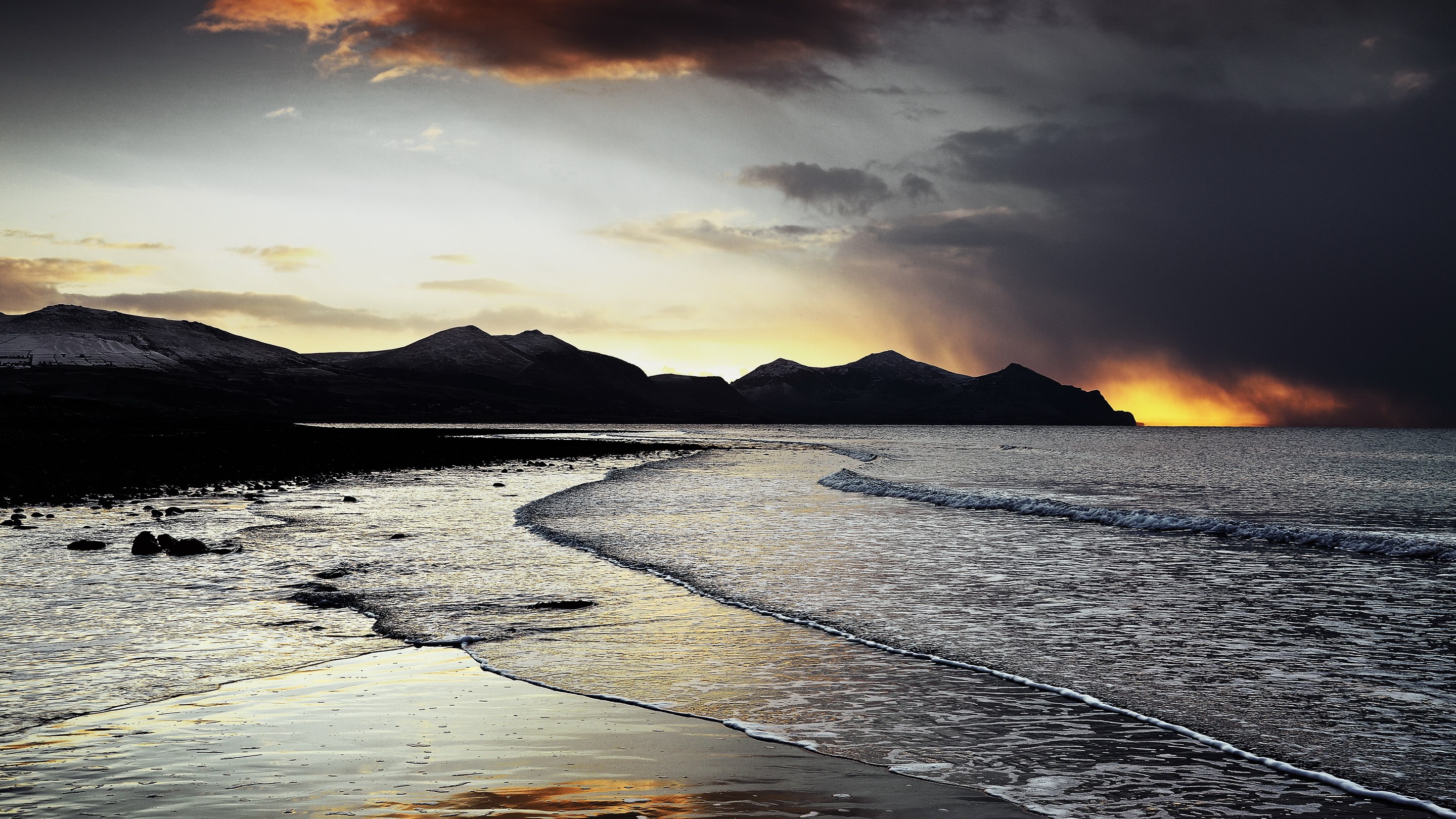 Stormy sunset over a rocky beach and mountains HD Wallpaper
