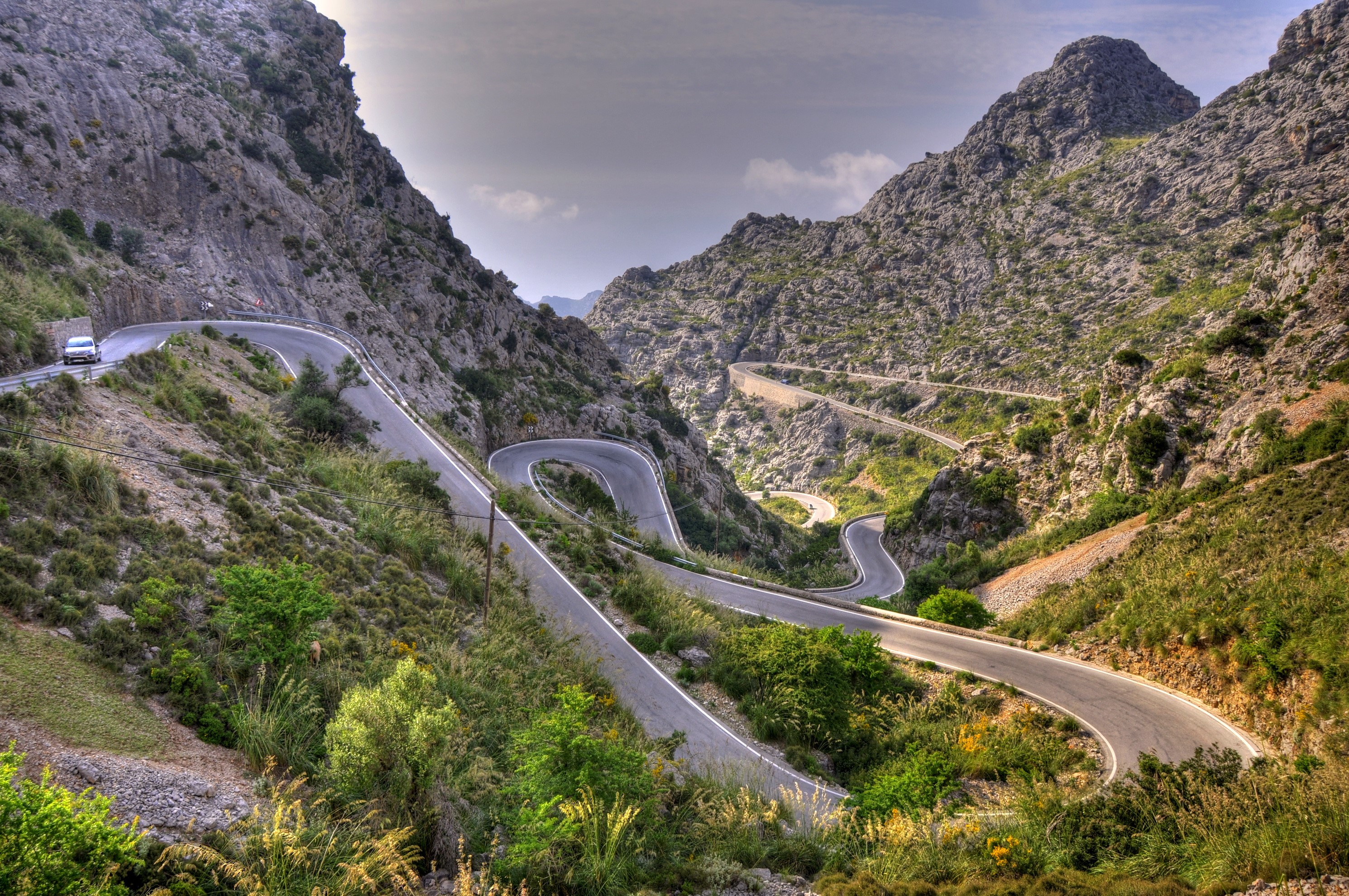 Winding mountain road with a car HD Wallpaper
