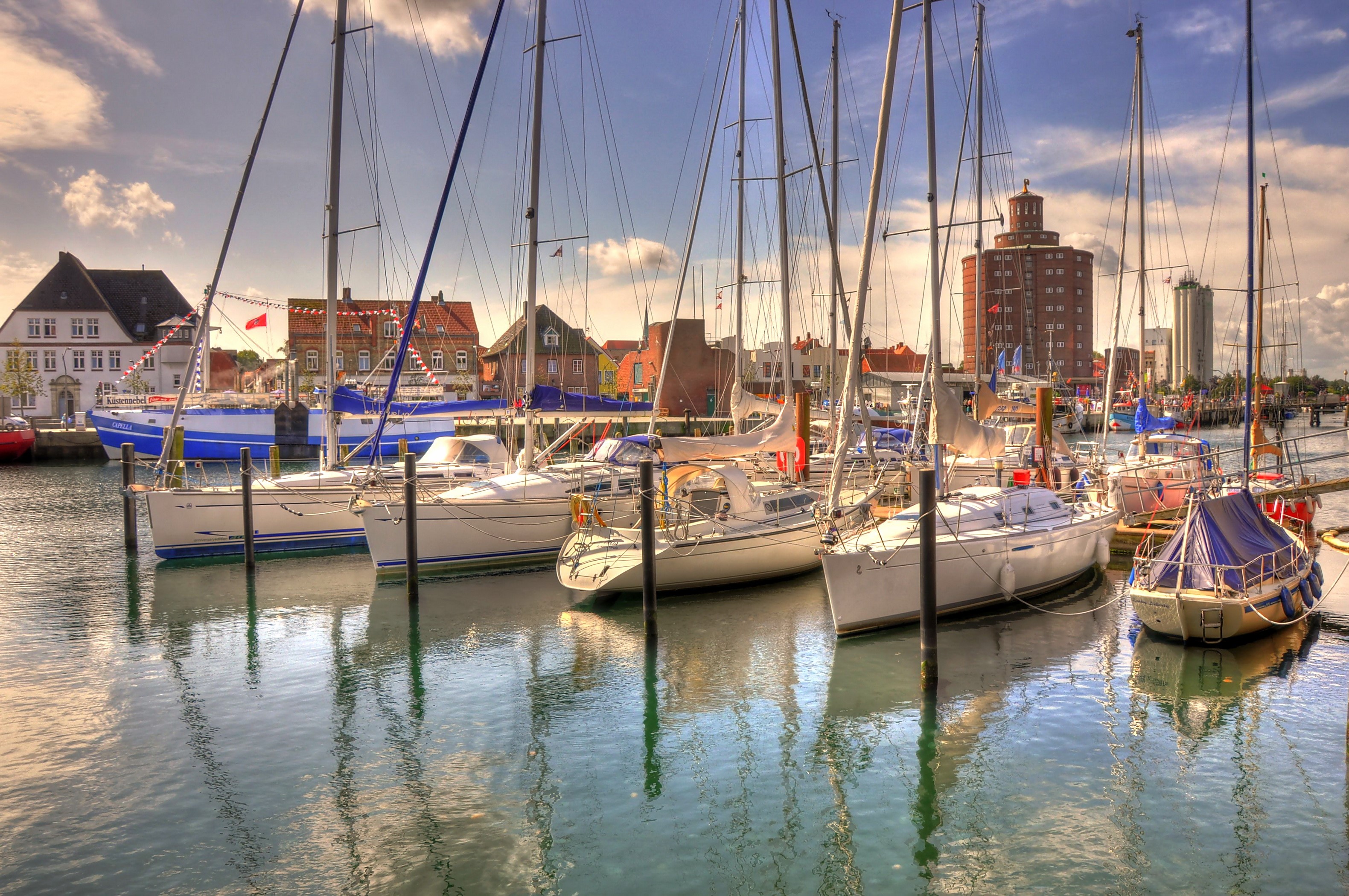 Sailboats docked in a harbor with buildings in the background HD Wallpaper
