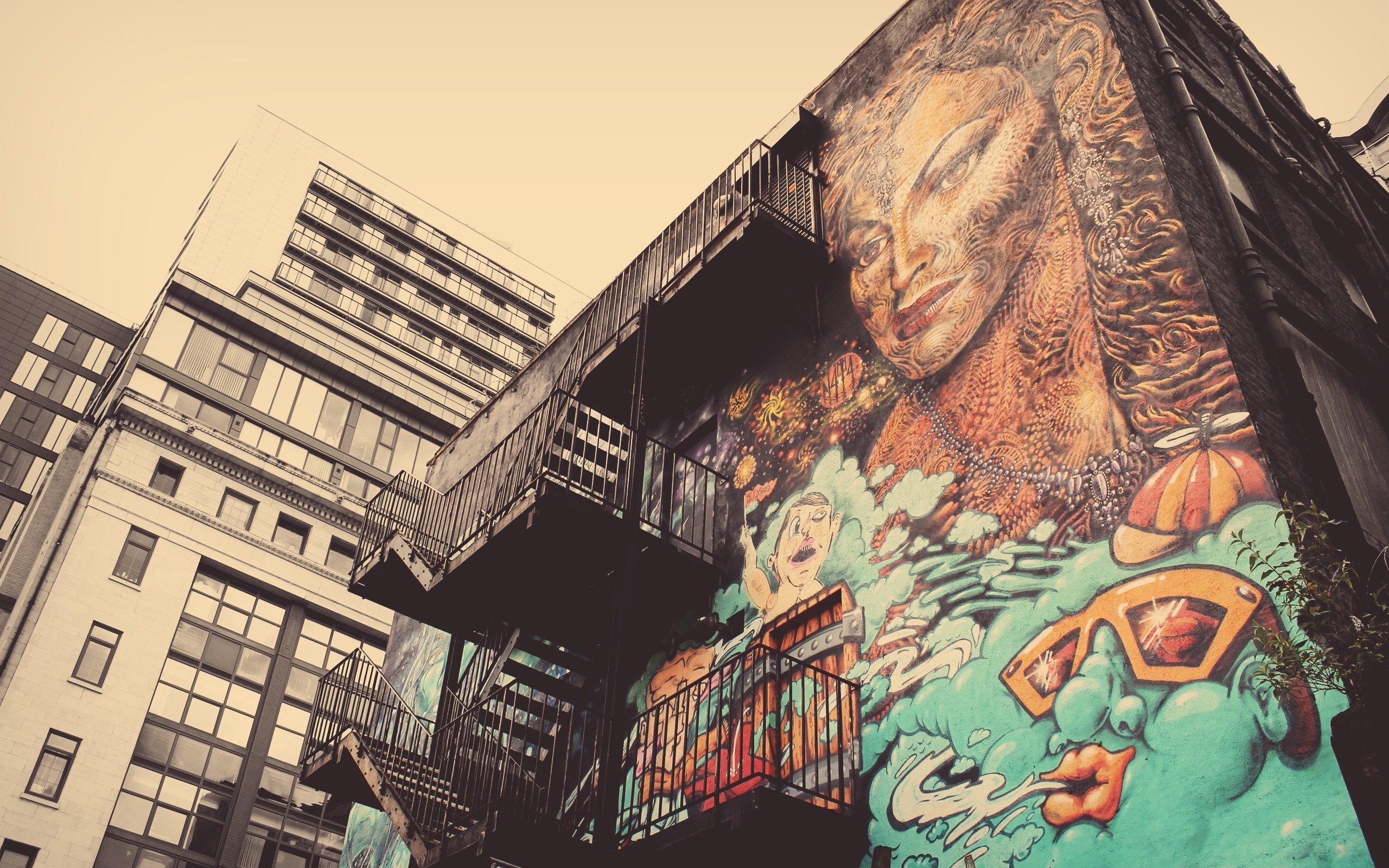Graffiti mural of a woman's face and sunglasses on a building HD Wallpaper