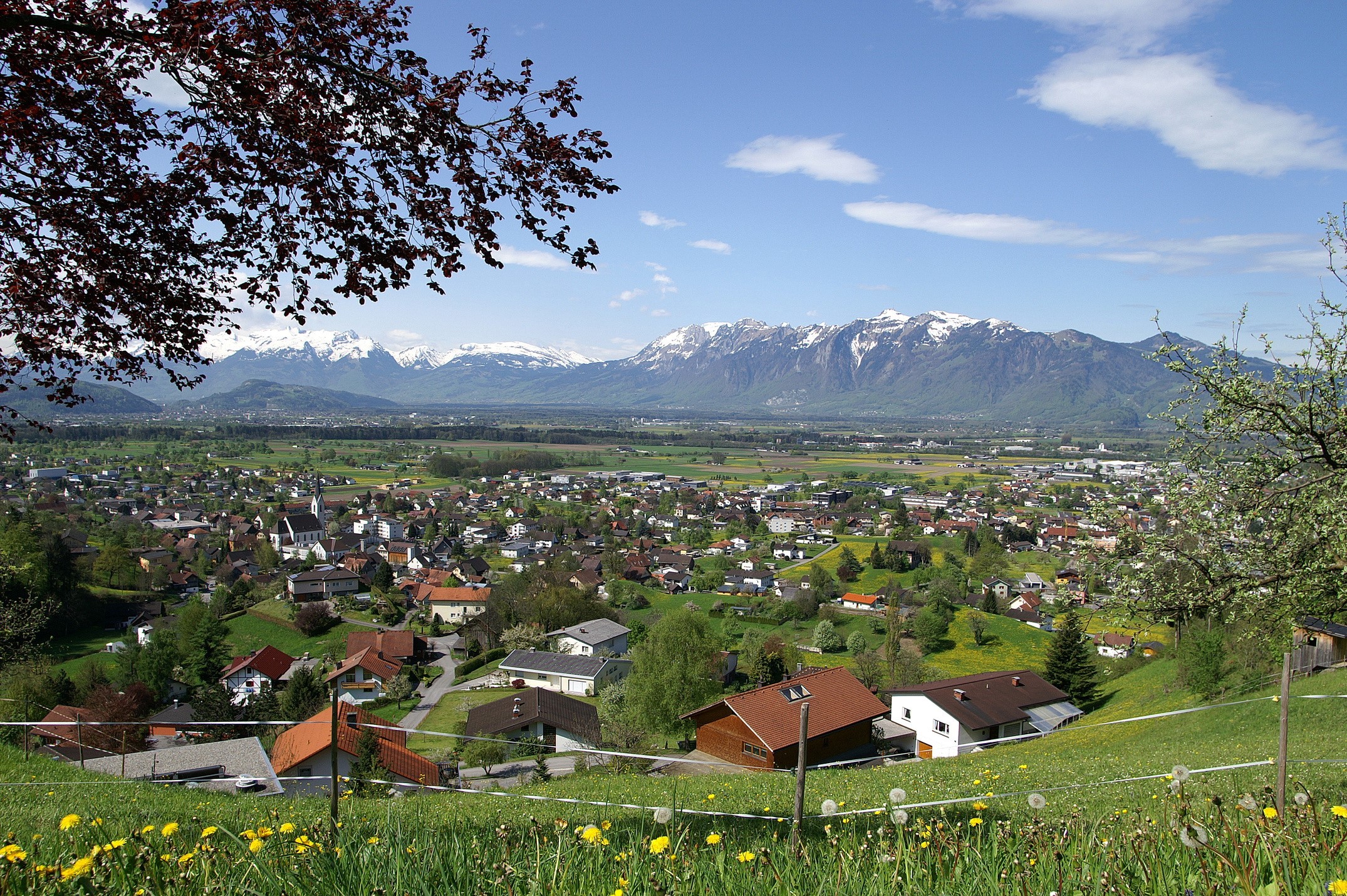 Village with snow-capped mountains in the background HD Wallpaper