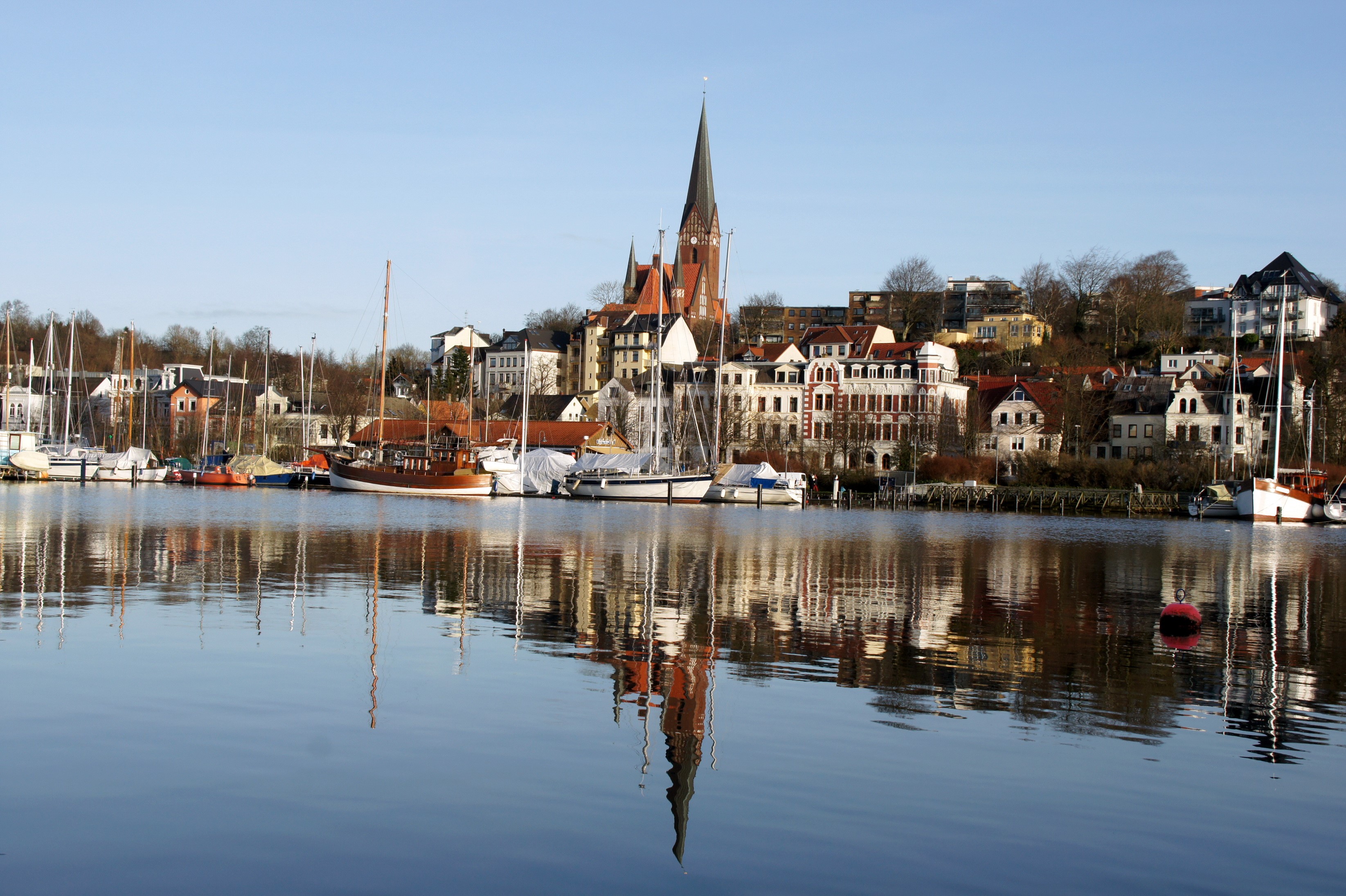 Boats docked in a harbor with a German town in the background HD Wallpaper