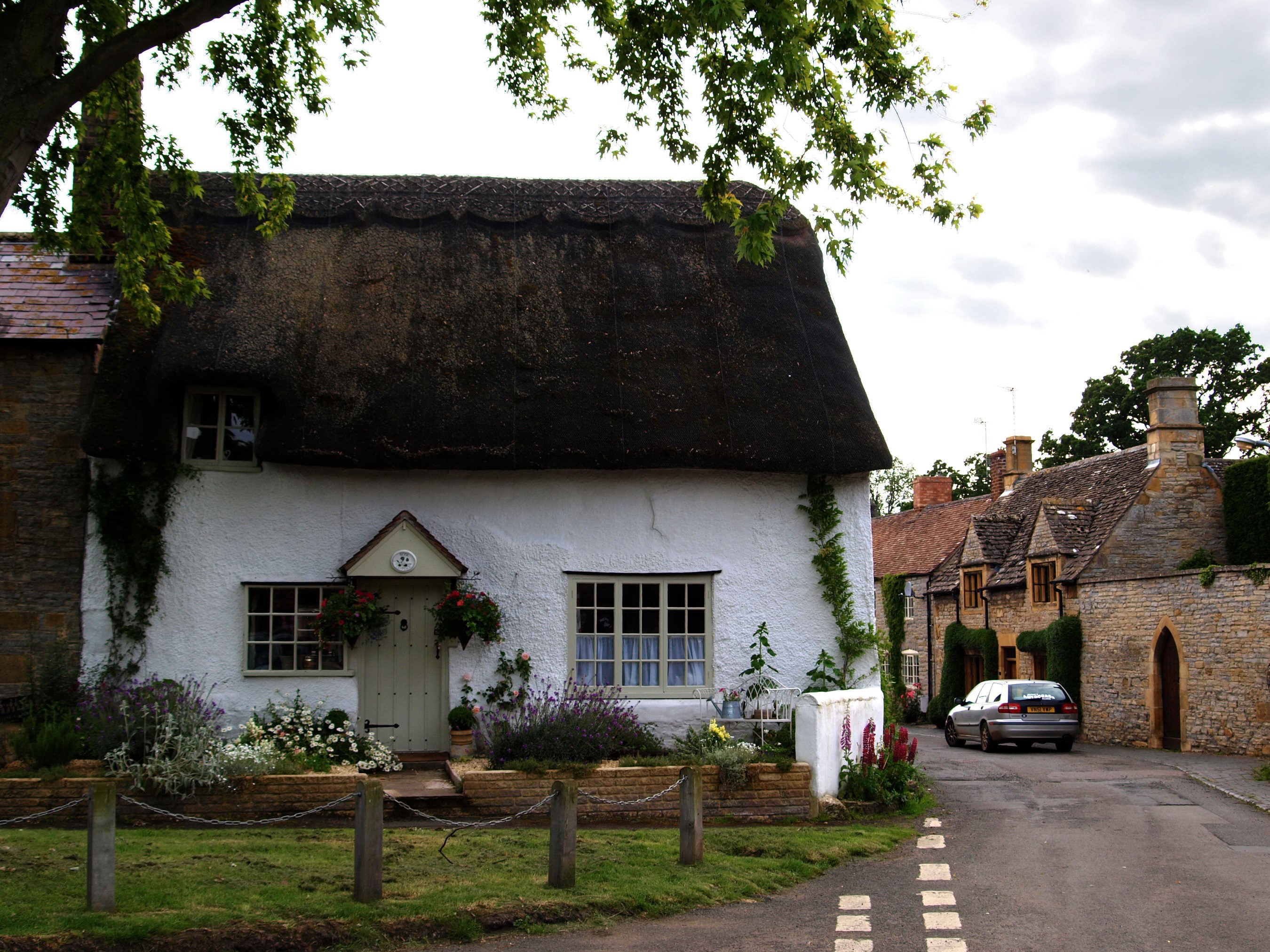 Thatched cottage and stone houses in a village HD Wallpaper