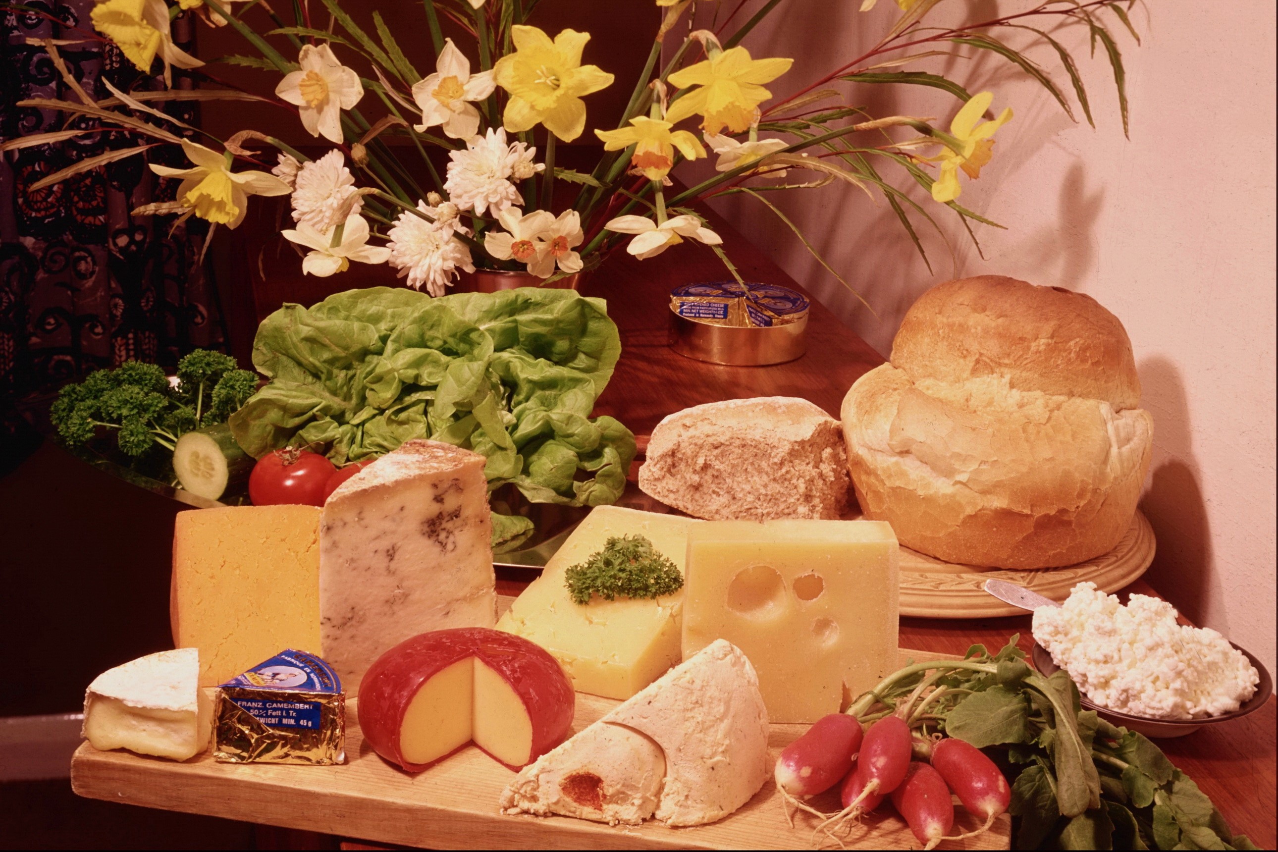 Assortment of cheeses with bread, lettuce, and flowers HD Wallpaper