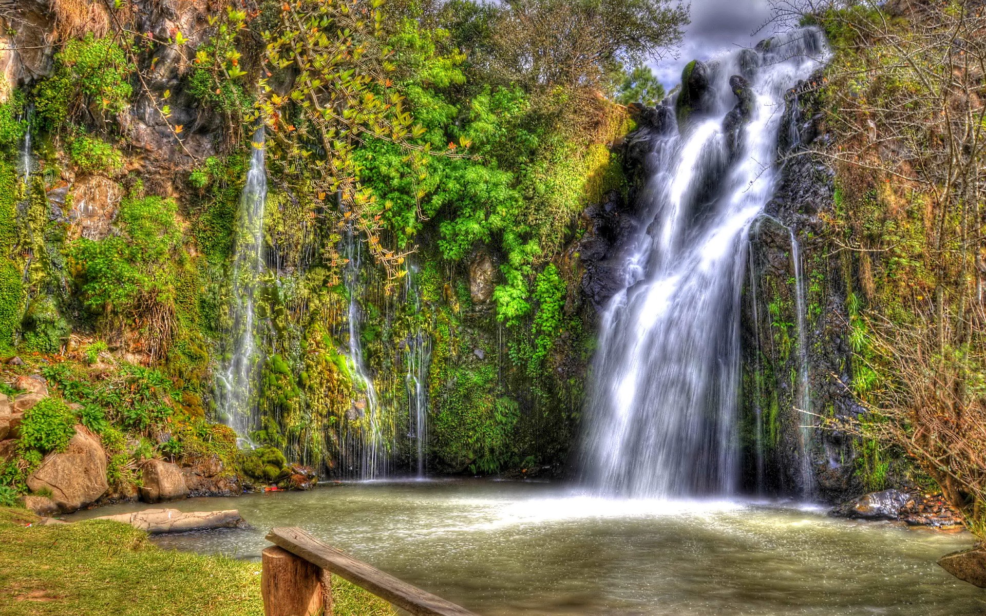 Waterfalls cascading down mossy rocks into a pool HD Wallpaper