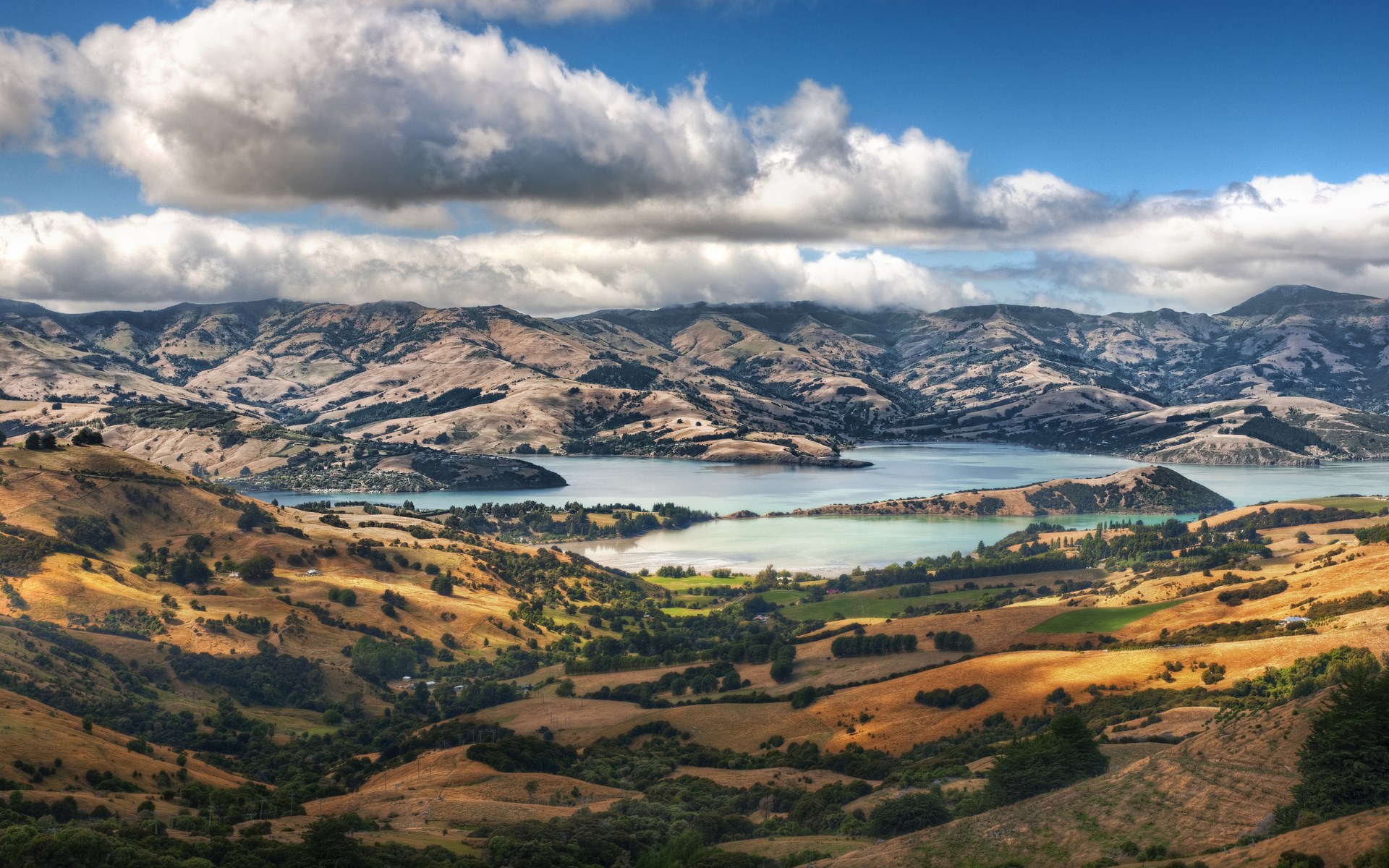 Rolling hills and a bay under a cloudy sky HD Wallpaper