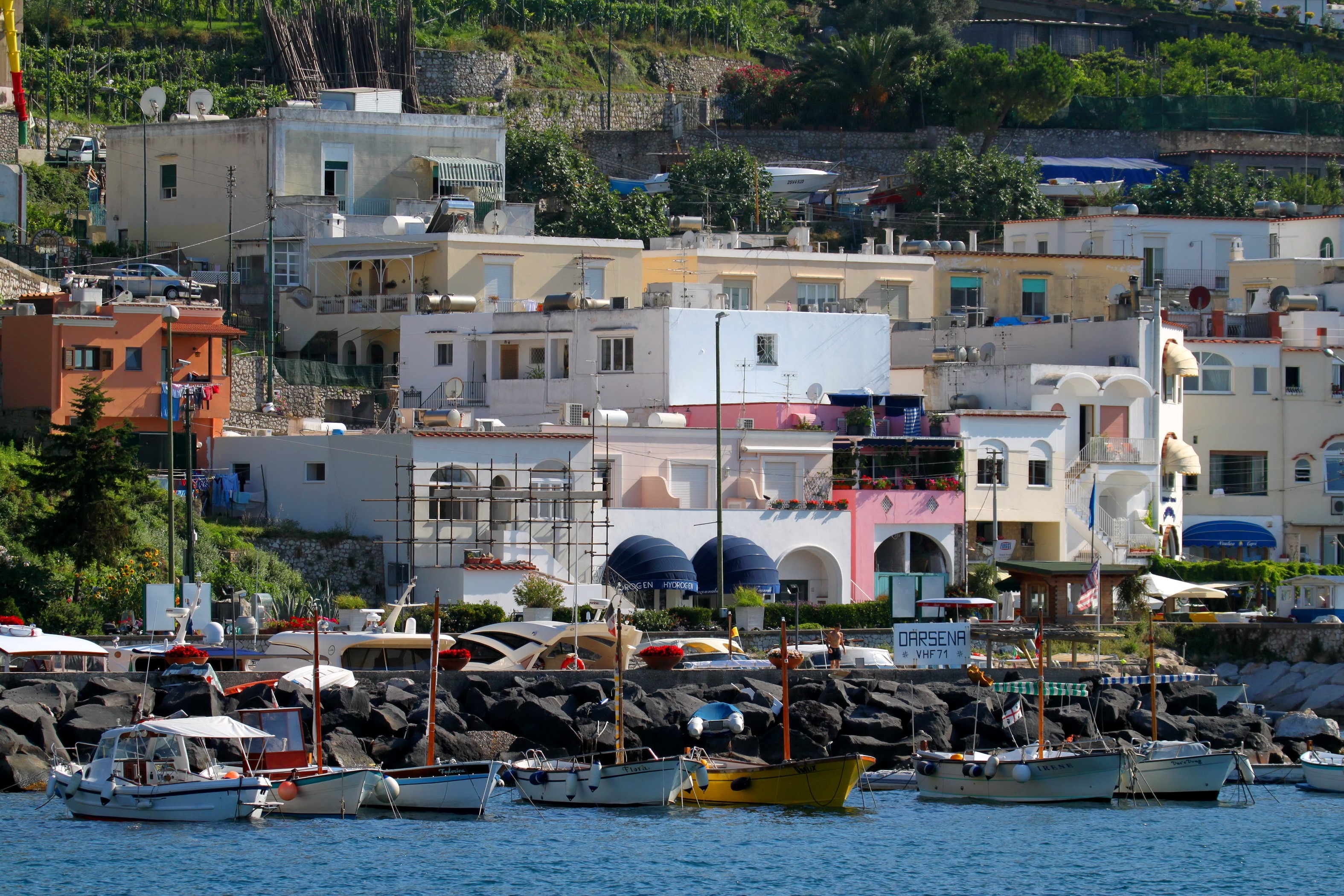 Boats docked in a harbor with colorful buildings in Capri, Italy HD Wallpaper