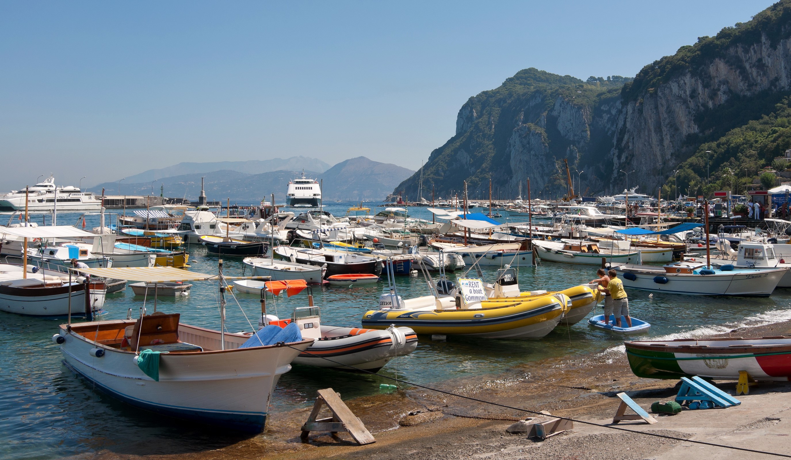 Boats docked in a harbor with a mountain in the background HD Wallpaper