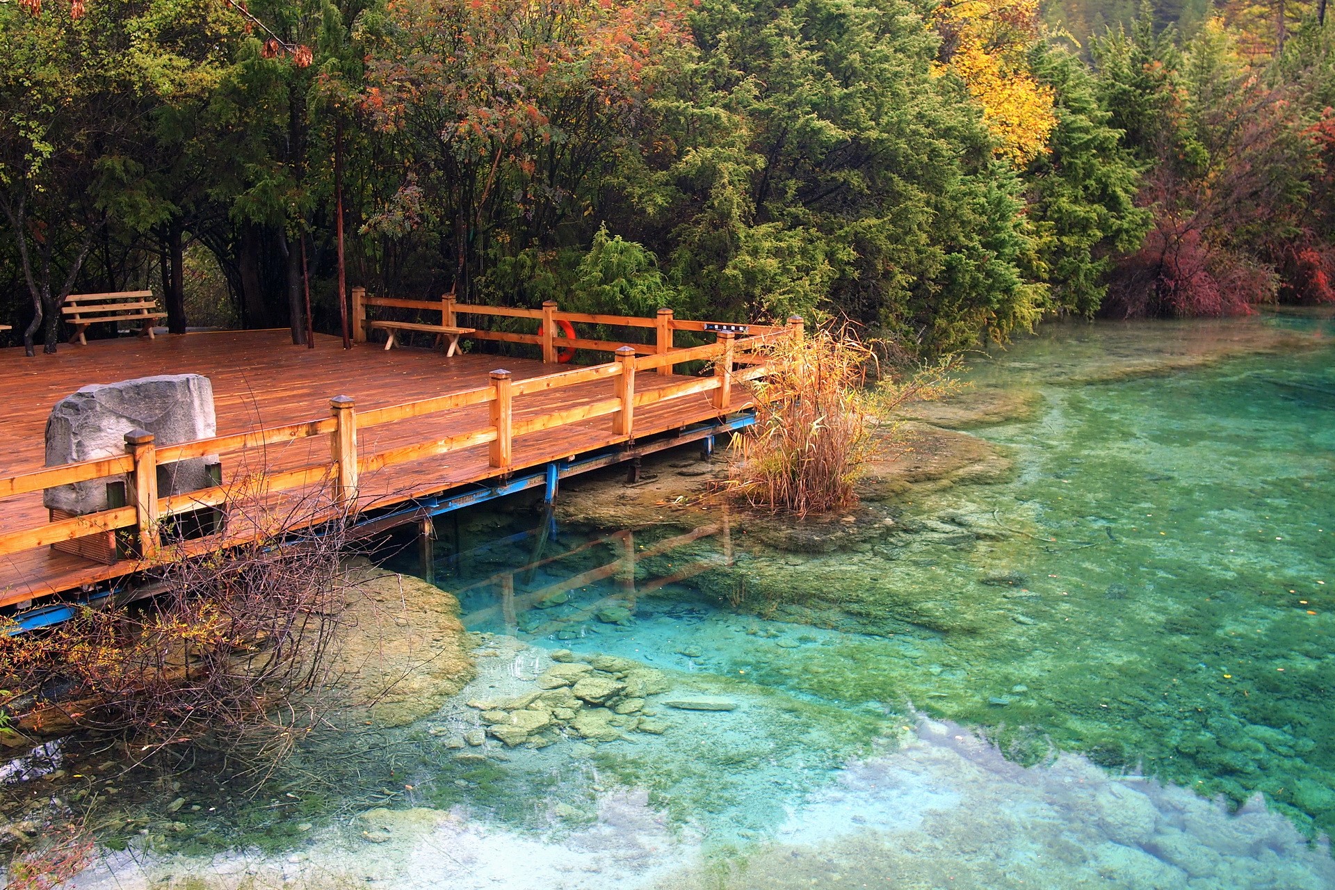 Wooden boardwalk over a clear turquoise lake in Jiuzhaigou National Park, China HD Wallpaper