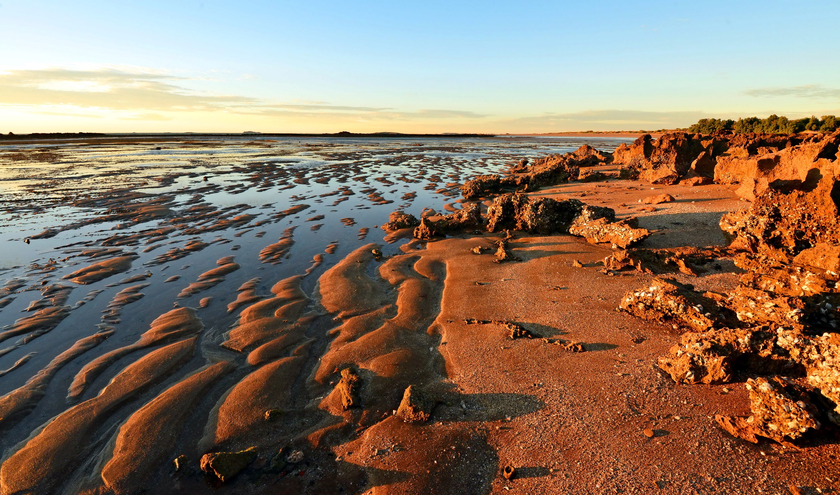 Beach with tidal pools and rocky shore at sunset HD Wallpaper