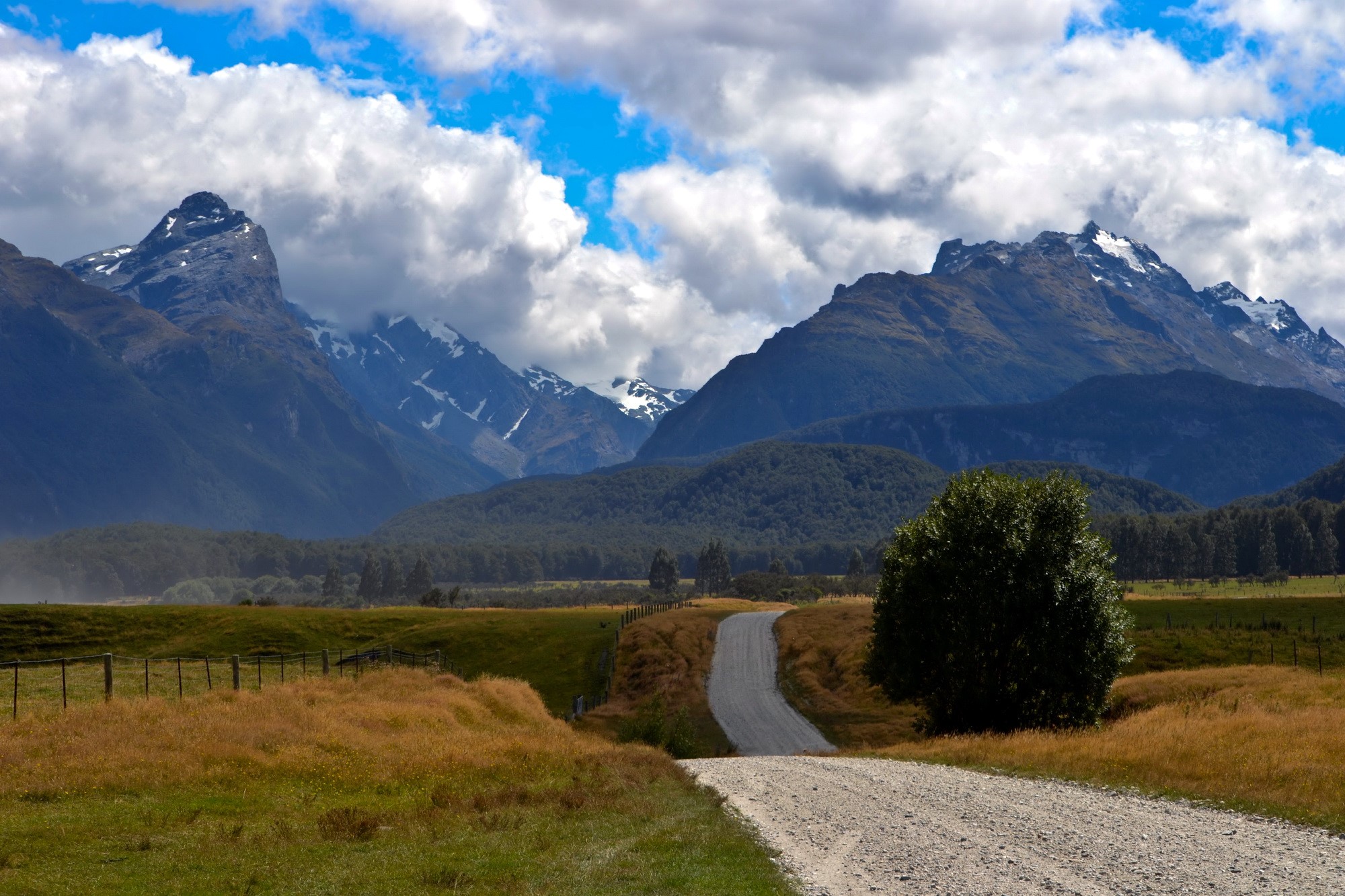 Gravel road leading to snow-capped mountains HD Wallpaper