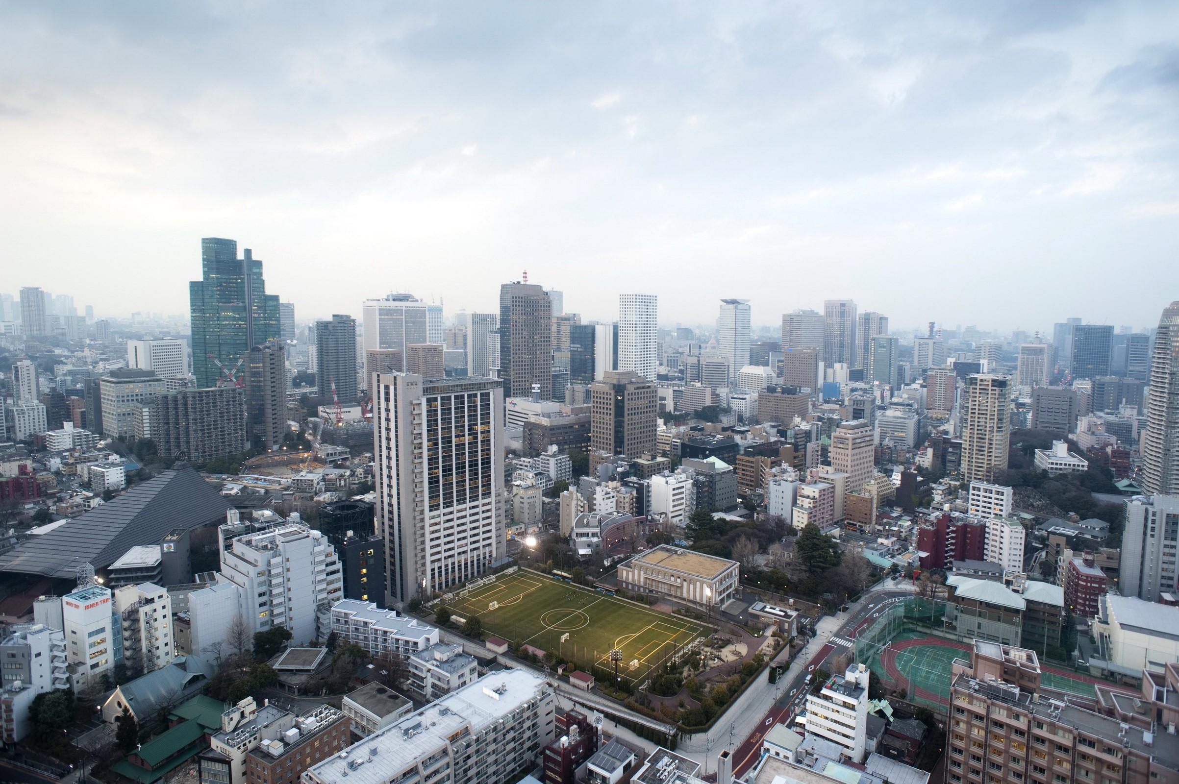 Aerial view of Tokyo cityscape with buildings and a soccer field HD Wallpaper