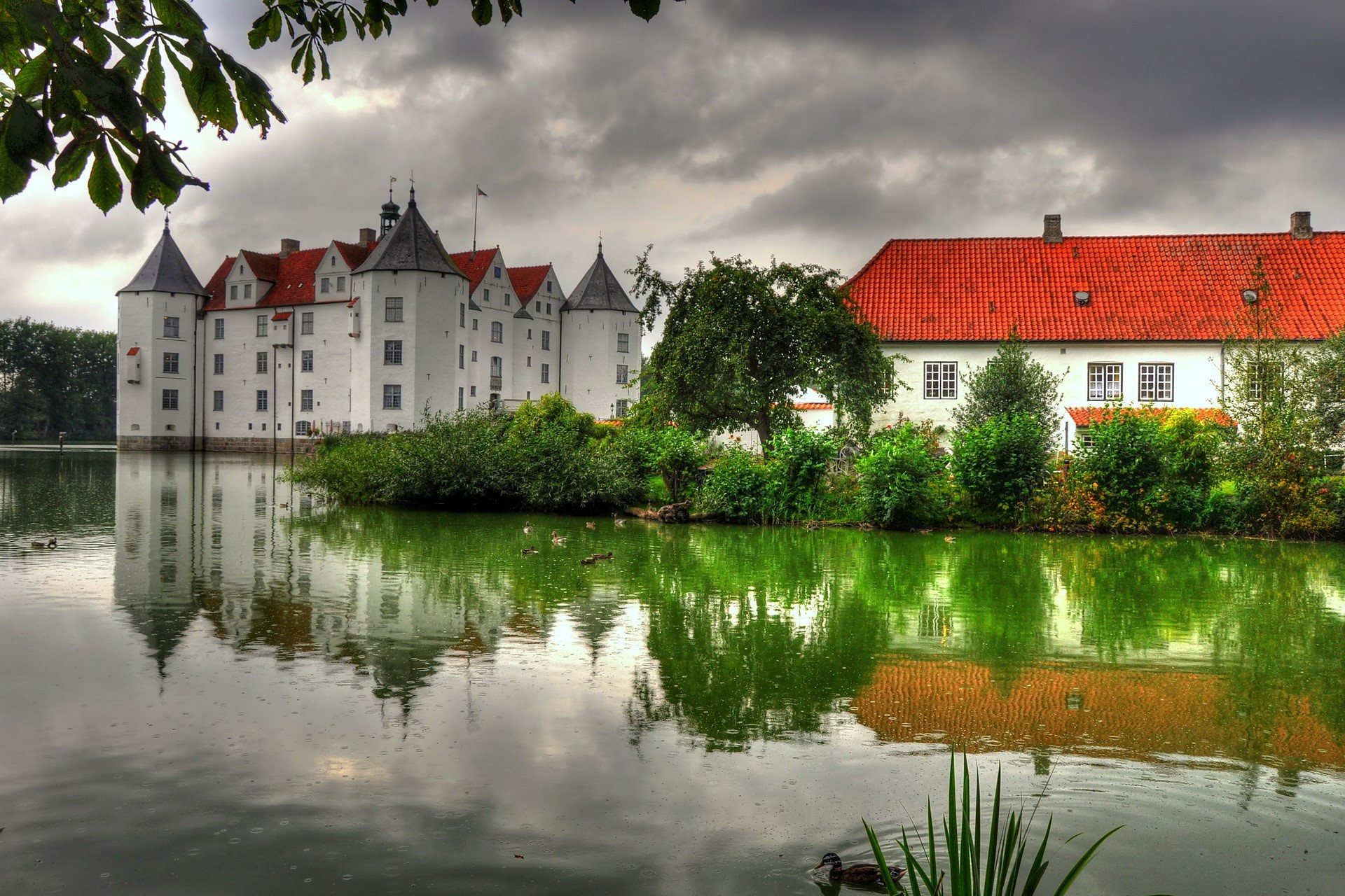 White castle with red roofs reflected in a lake HD Wallpaper
