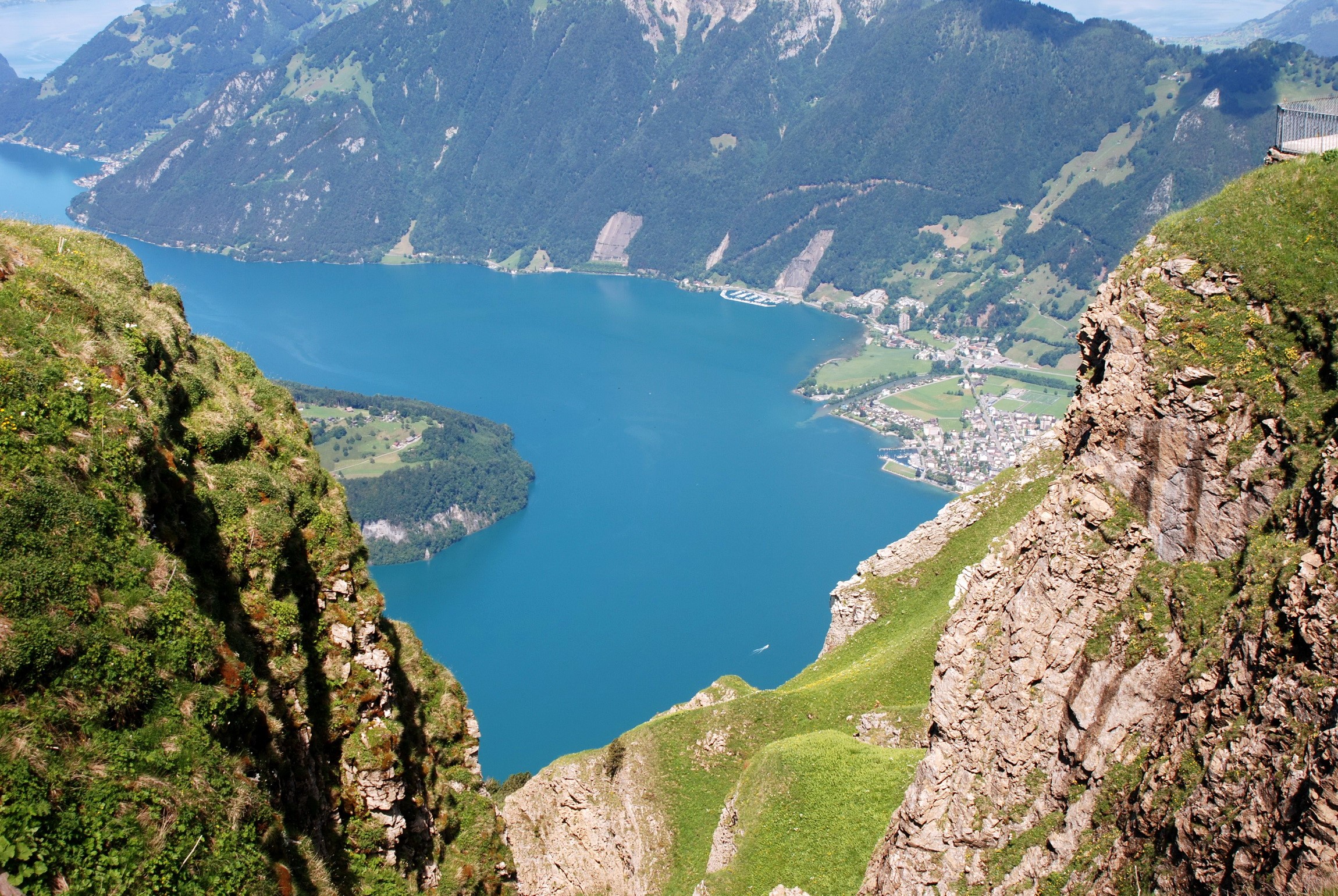 Turquoise lake surrounded by mountains and a town HD Wallpaper