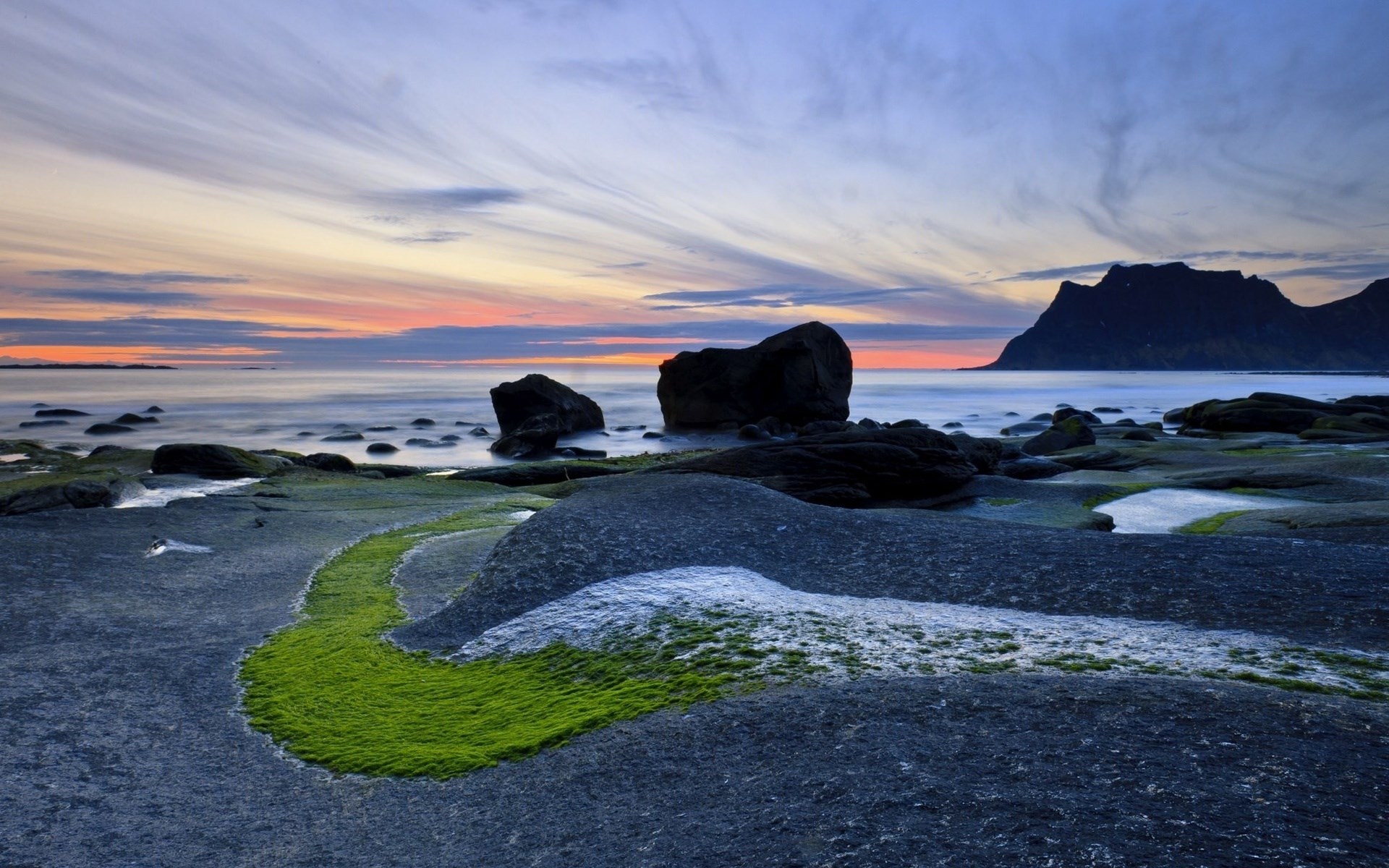 Rocky coastline with moss and mountain at sunset HD Wallpaper