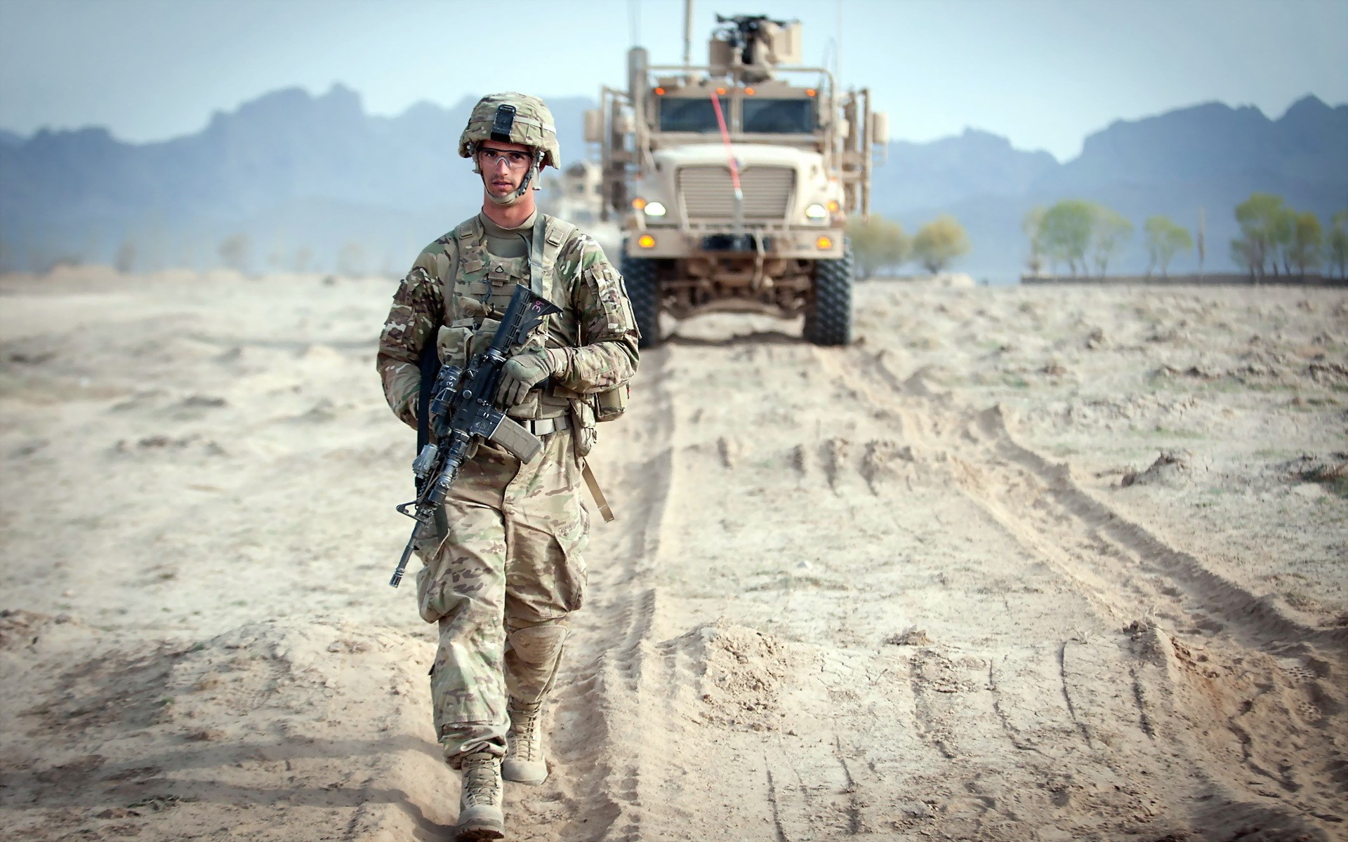 Soldier walking in desert with military vehicle HD Wallpaper