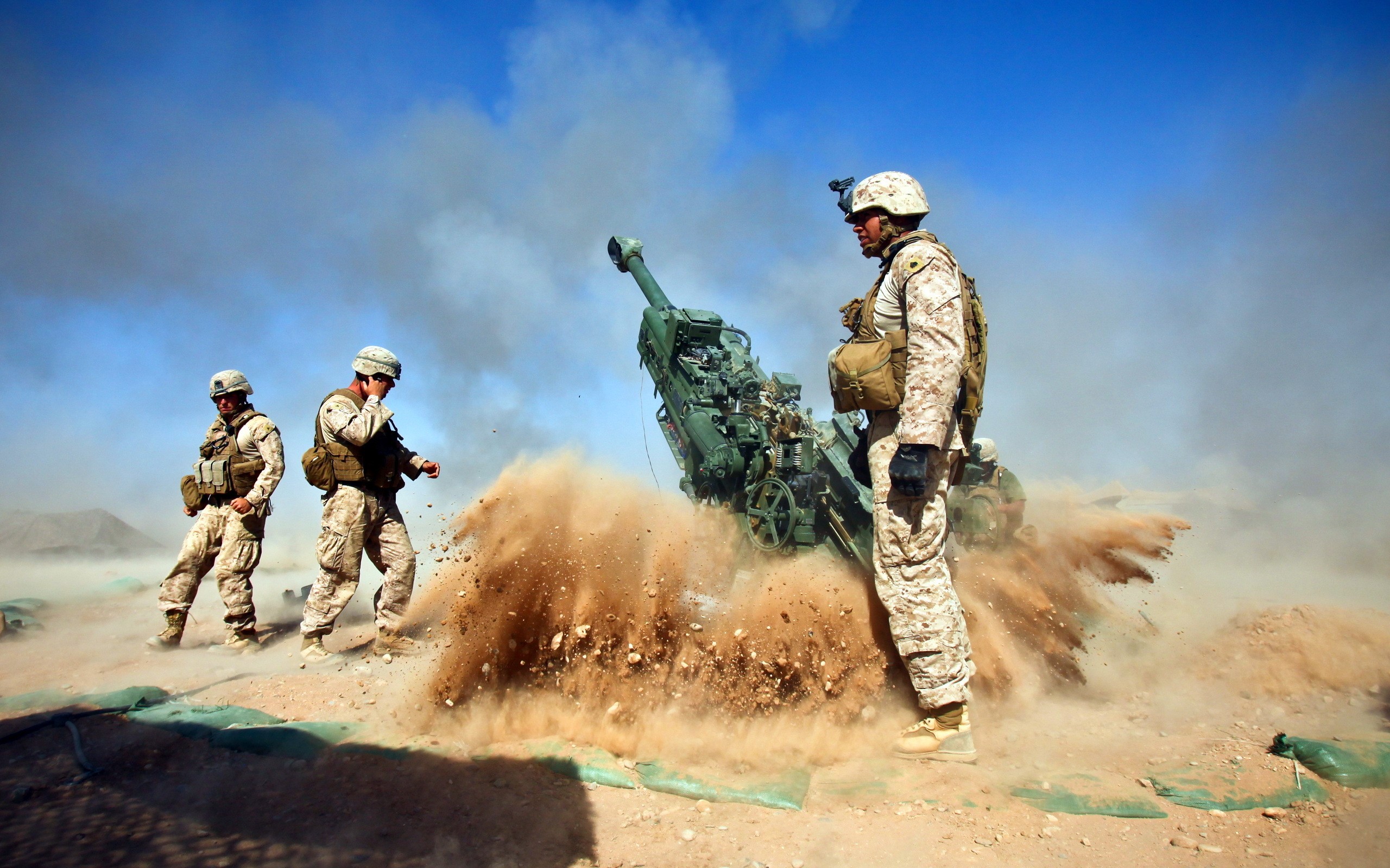 Marines firing a cannon in a desert HD Wallpaper