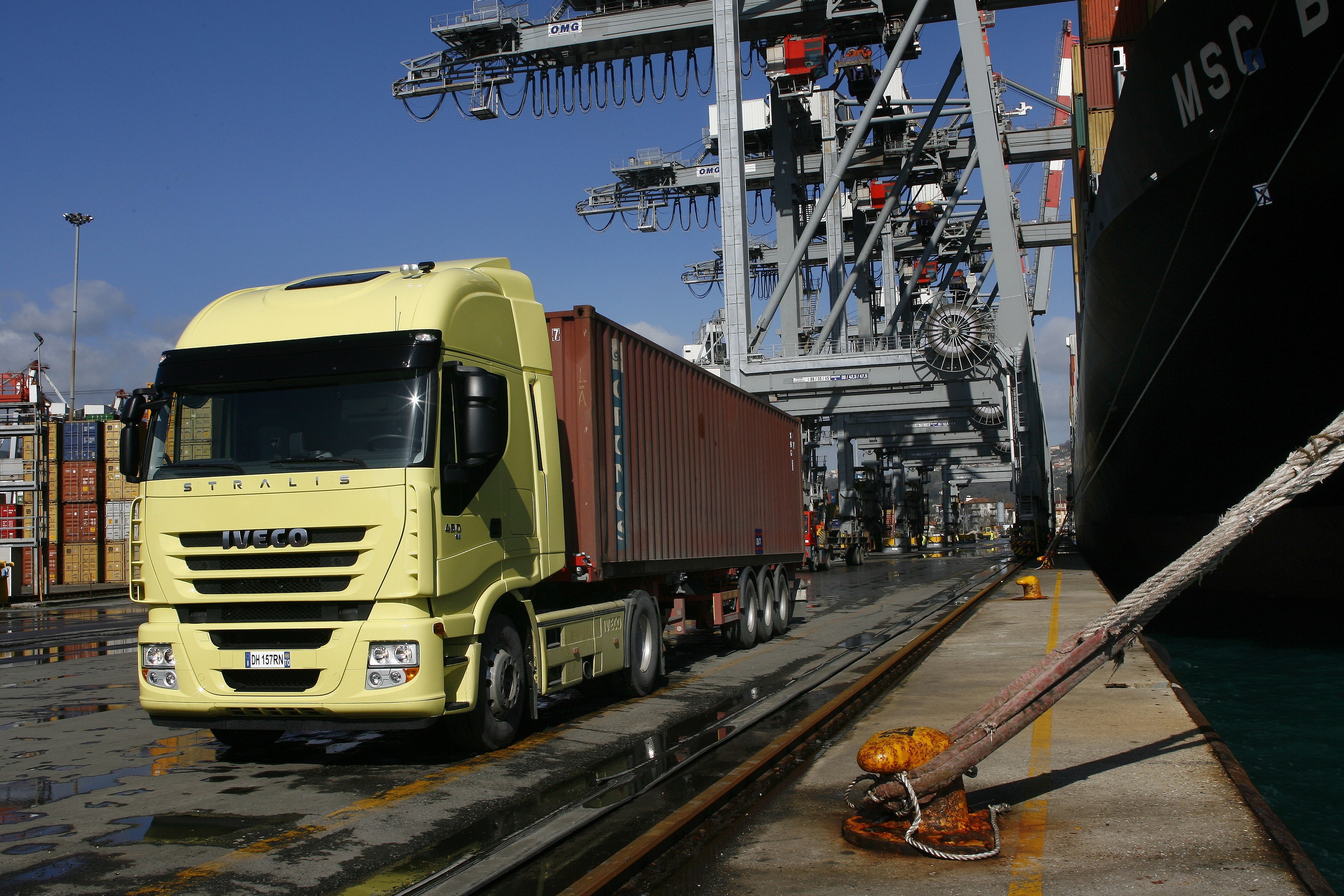 Yellow Iveco Stralis Truck at Port with Ship and Cranes HD Wallpaper