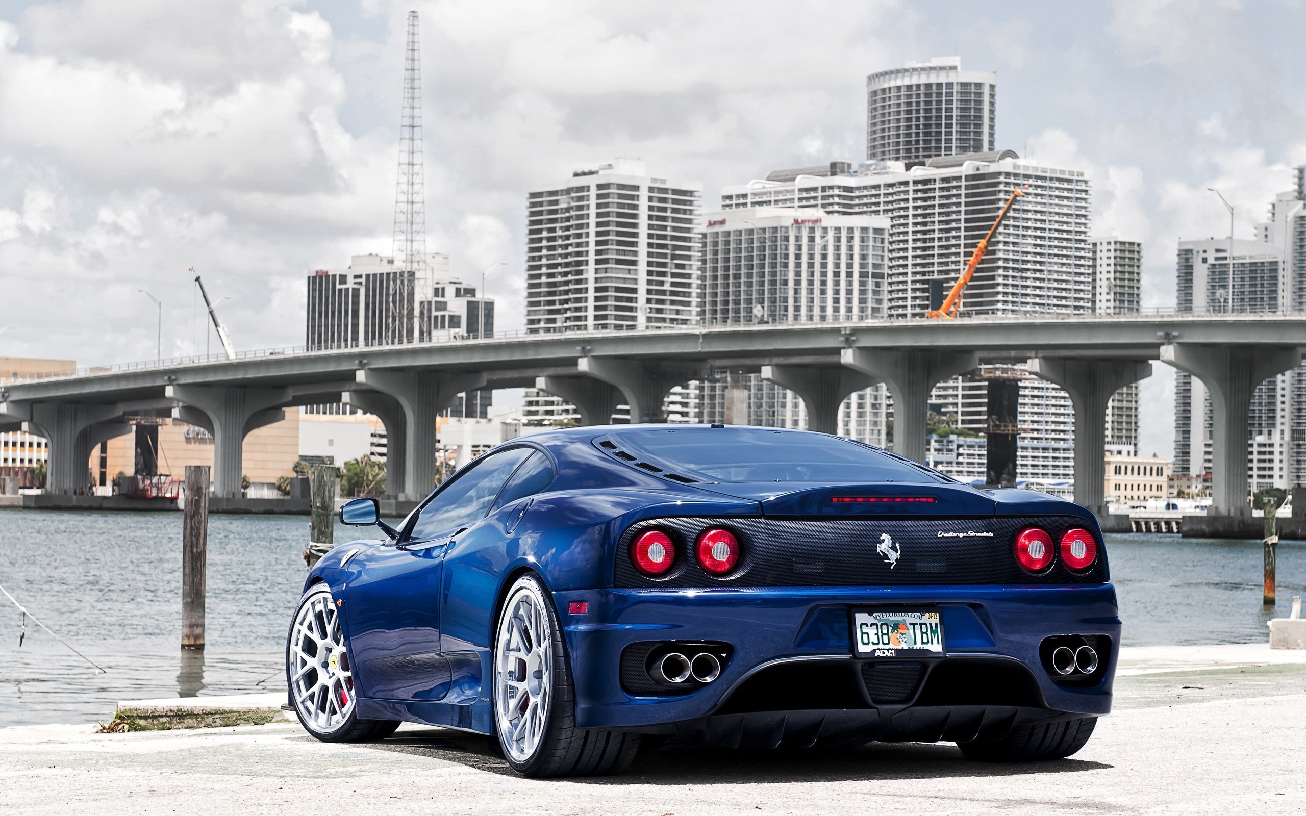 Blue Ferrari 360 Modena parked by water with city skyline HD Wallpaper