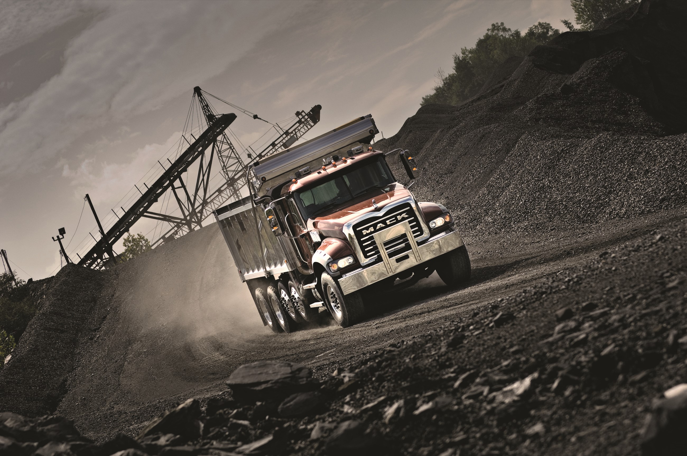 Mack dump truck driving on a dirt road with coal piles HD Wallpaper