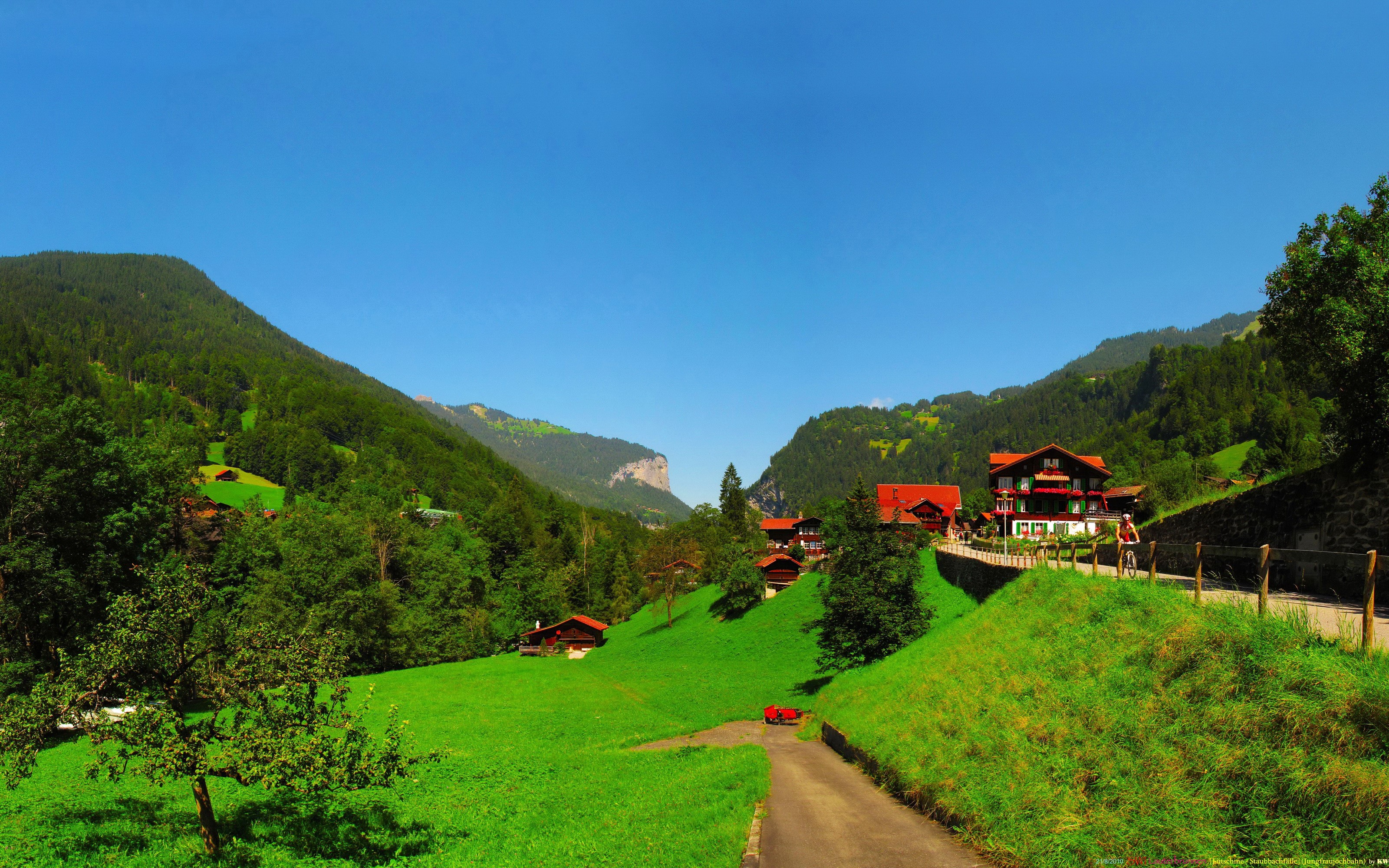 Alpine village with traditional houses and green meadows in Switzerland HD Wallpaper