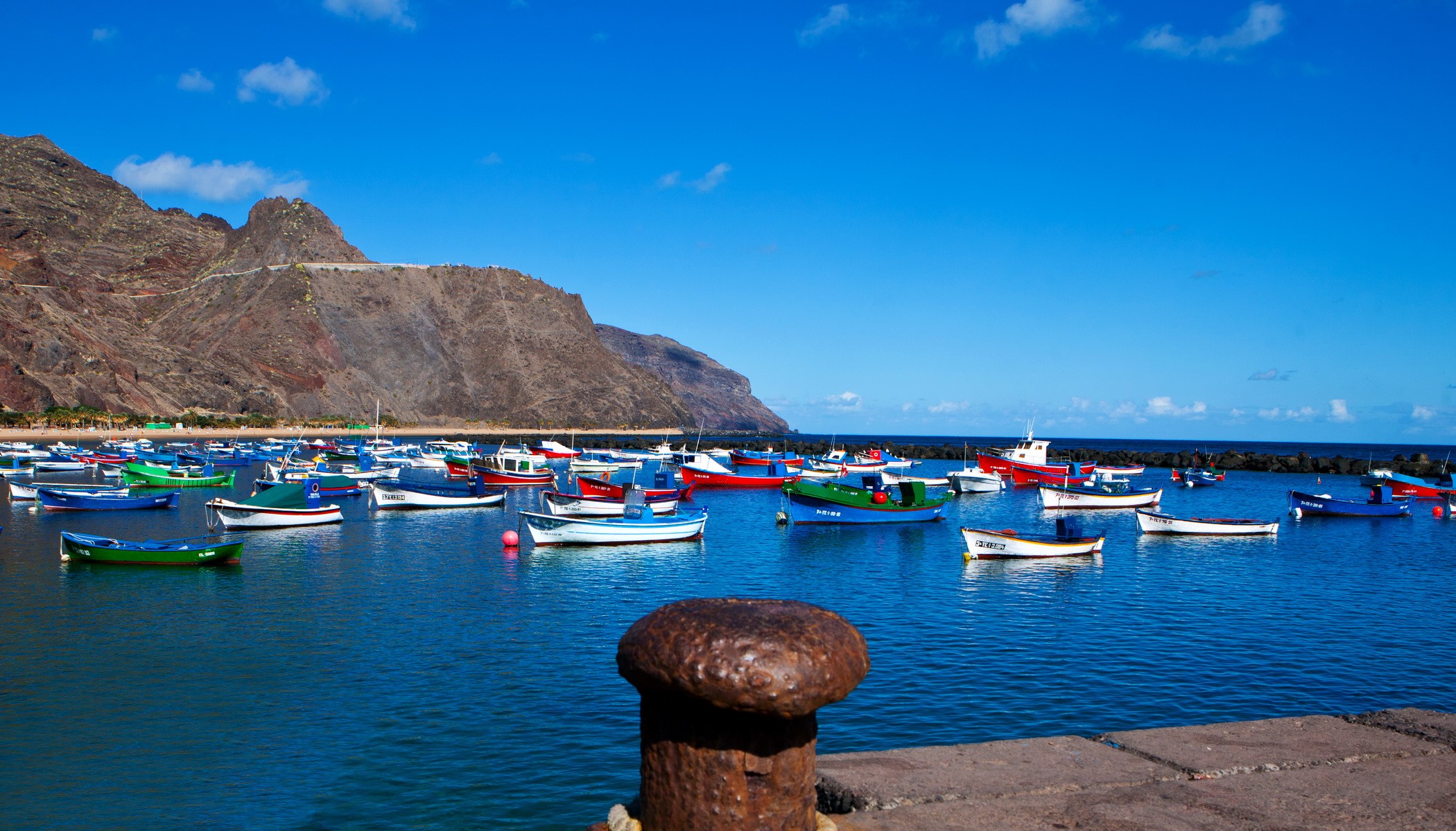 Colorful fishing boats moored in a harbor with mountains HD Wallpaper
