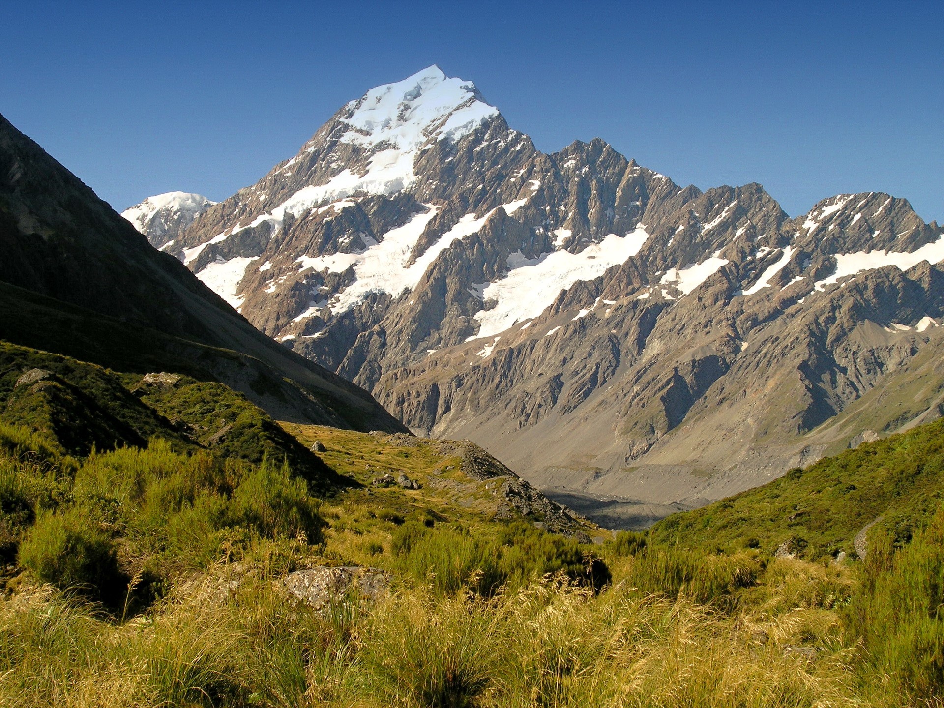 Snow-capped mountains in a valley with green grass HD Wallpaper