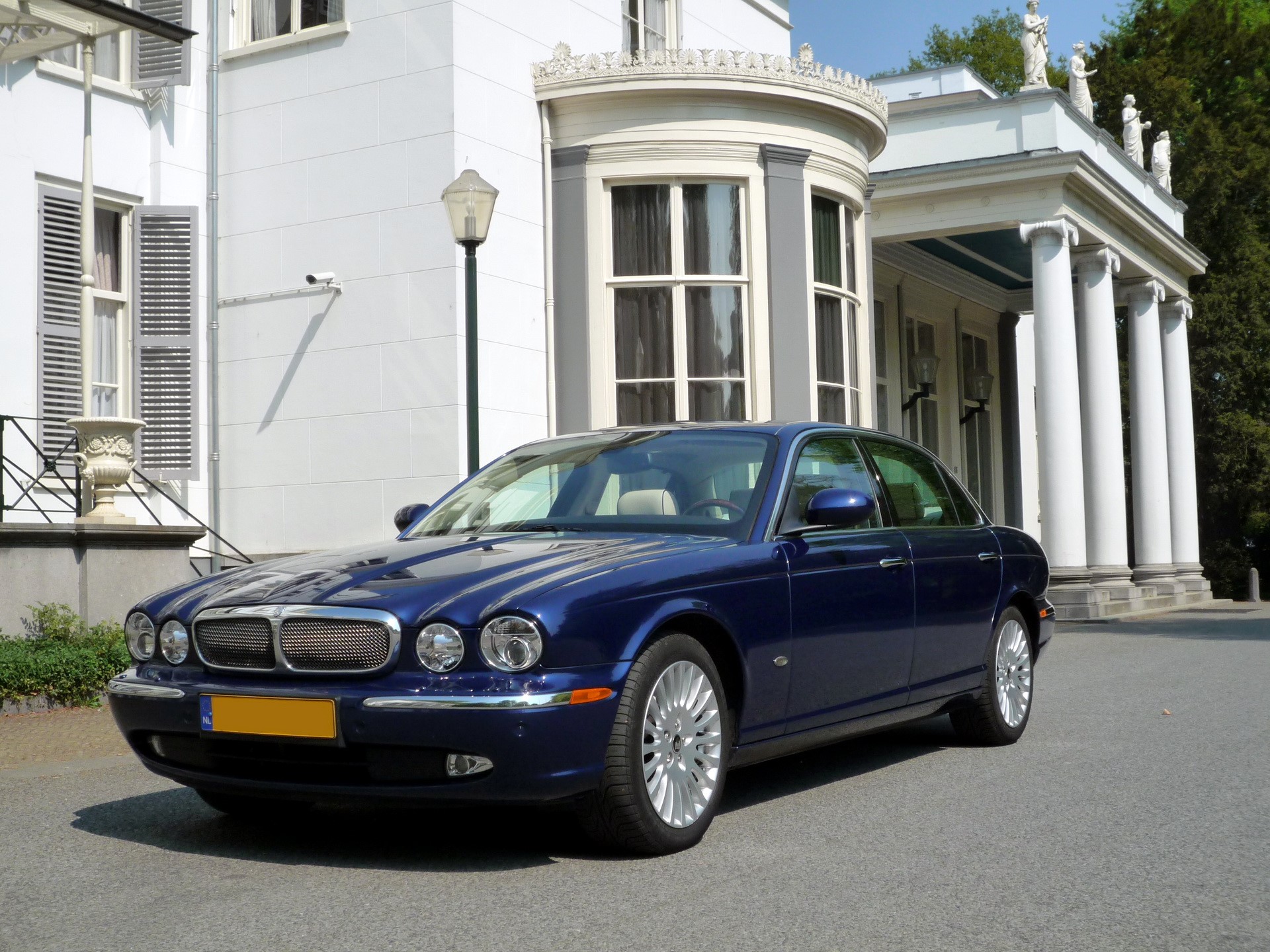 Blue 2006 Jaguar XJ parked in front of a white building HD Wallpaper