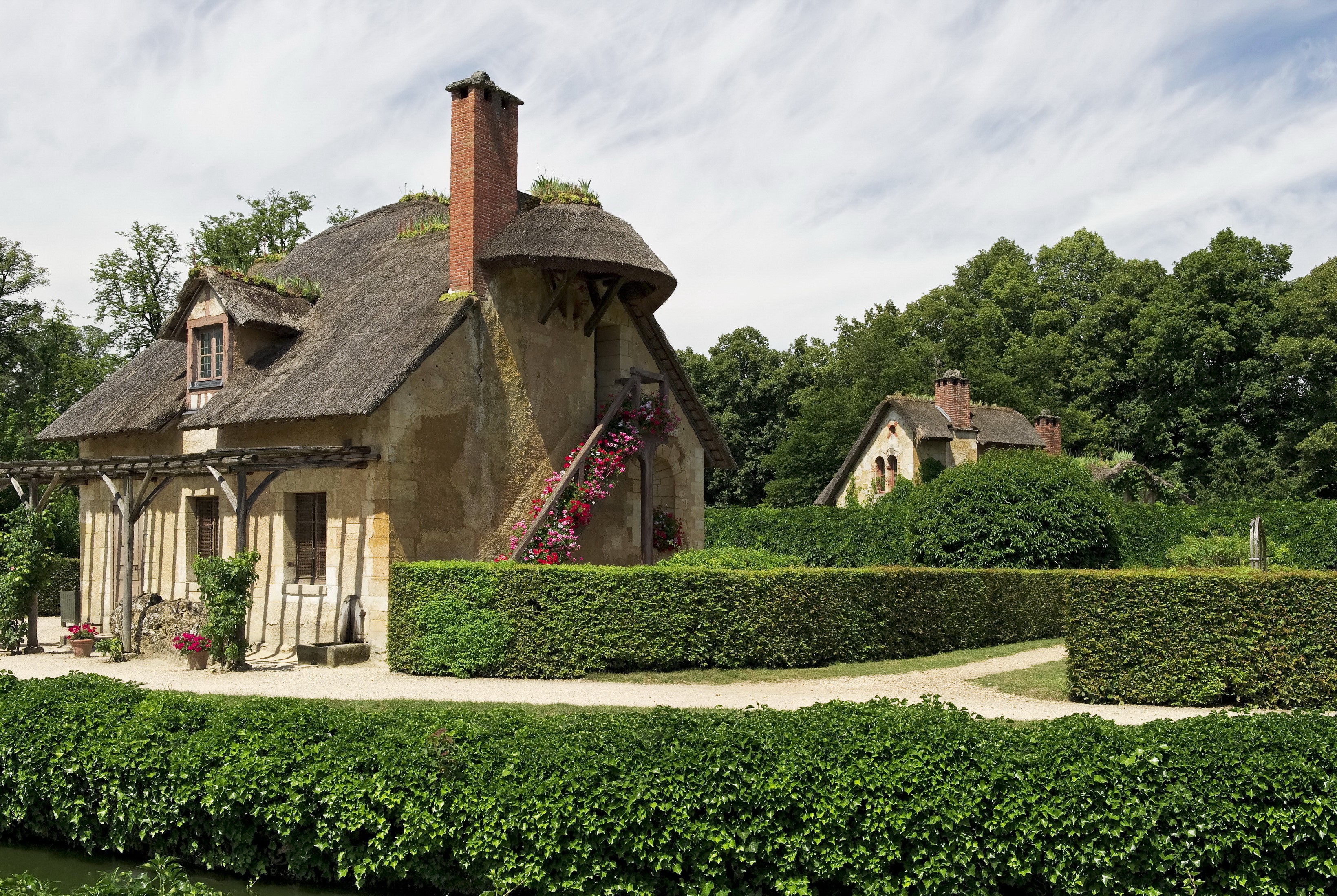 Thatched-roof cottages in a garden setting HD Wallpaper