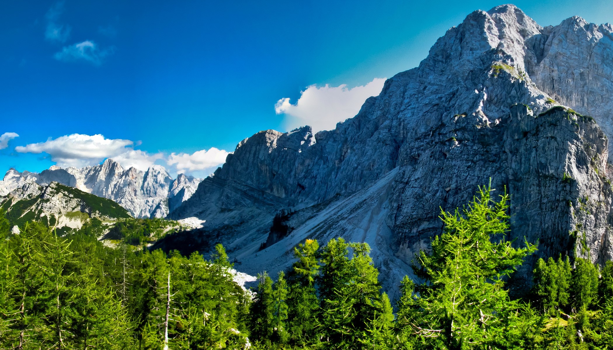 Jagged mountain peaks under a blue sky with clouds HD Wallpaper