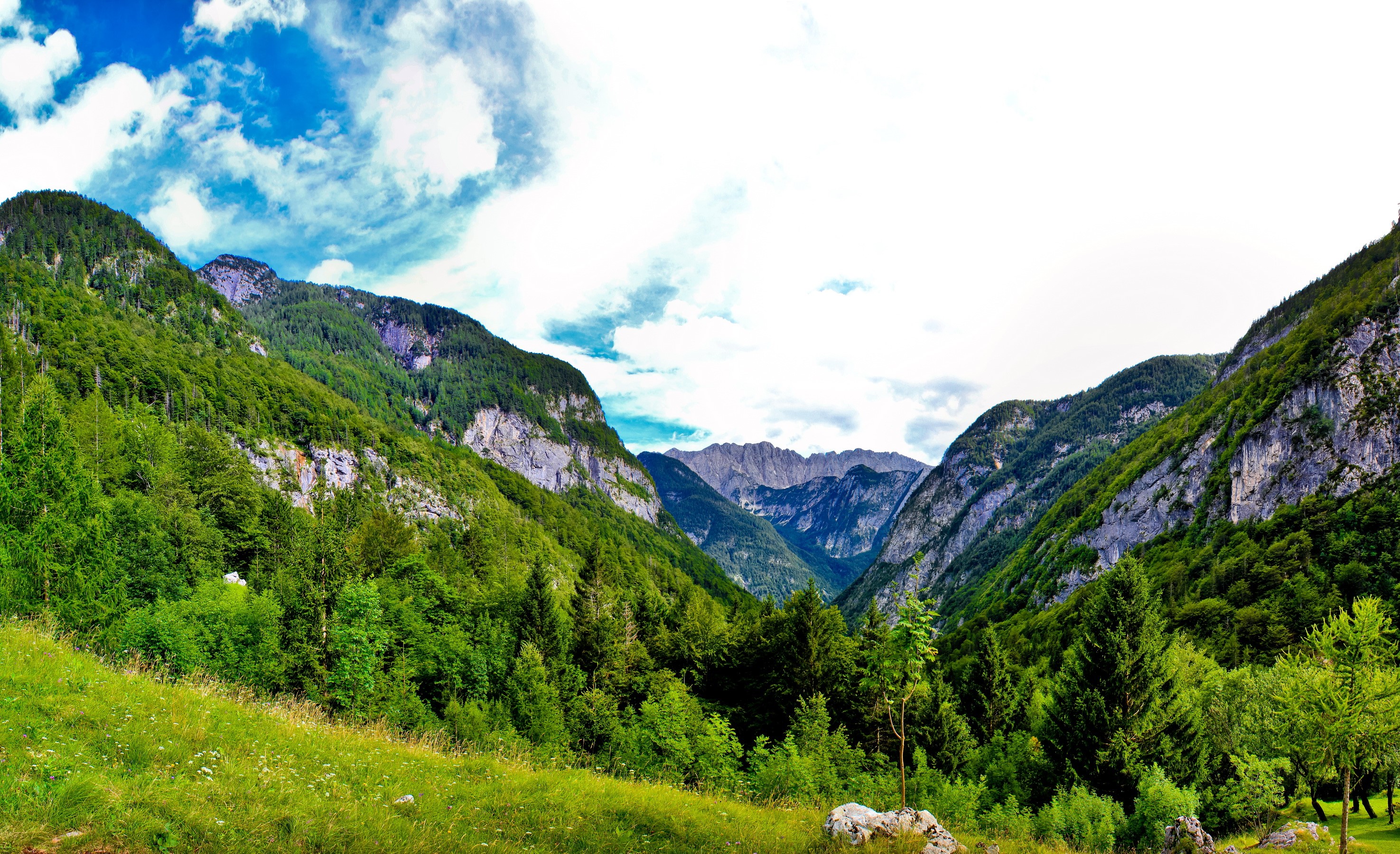 Green mountains under a cloudy blue sky HD Wallpaper