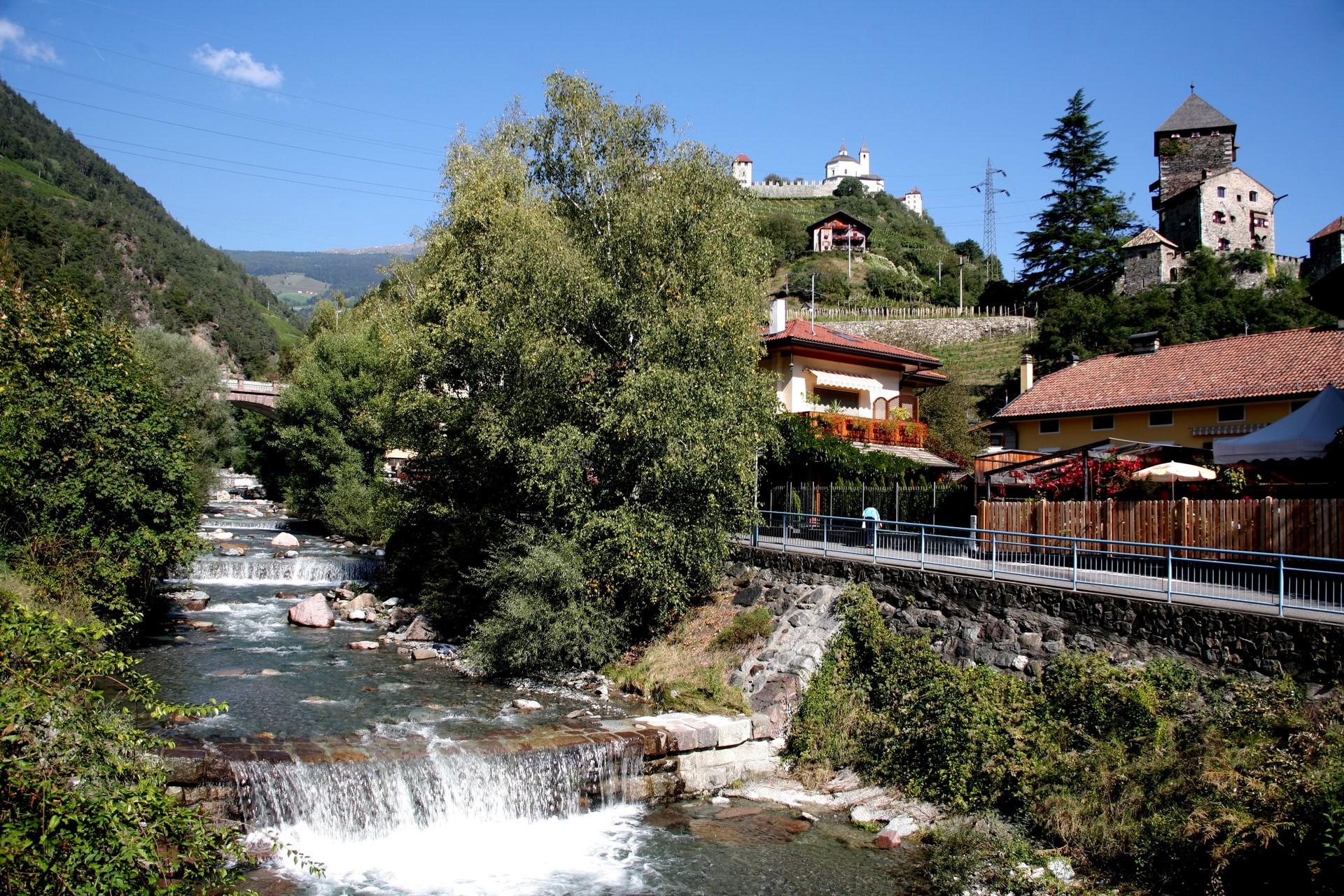 River flowing through a village with castles on a hill in Italy HD Wallpaper