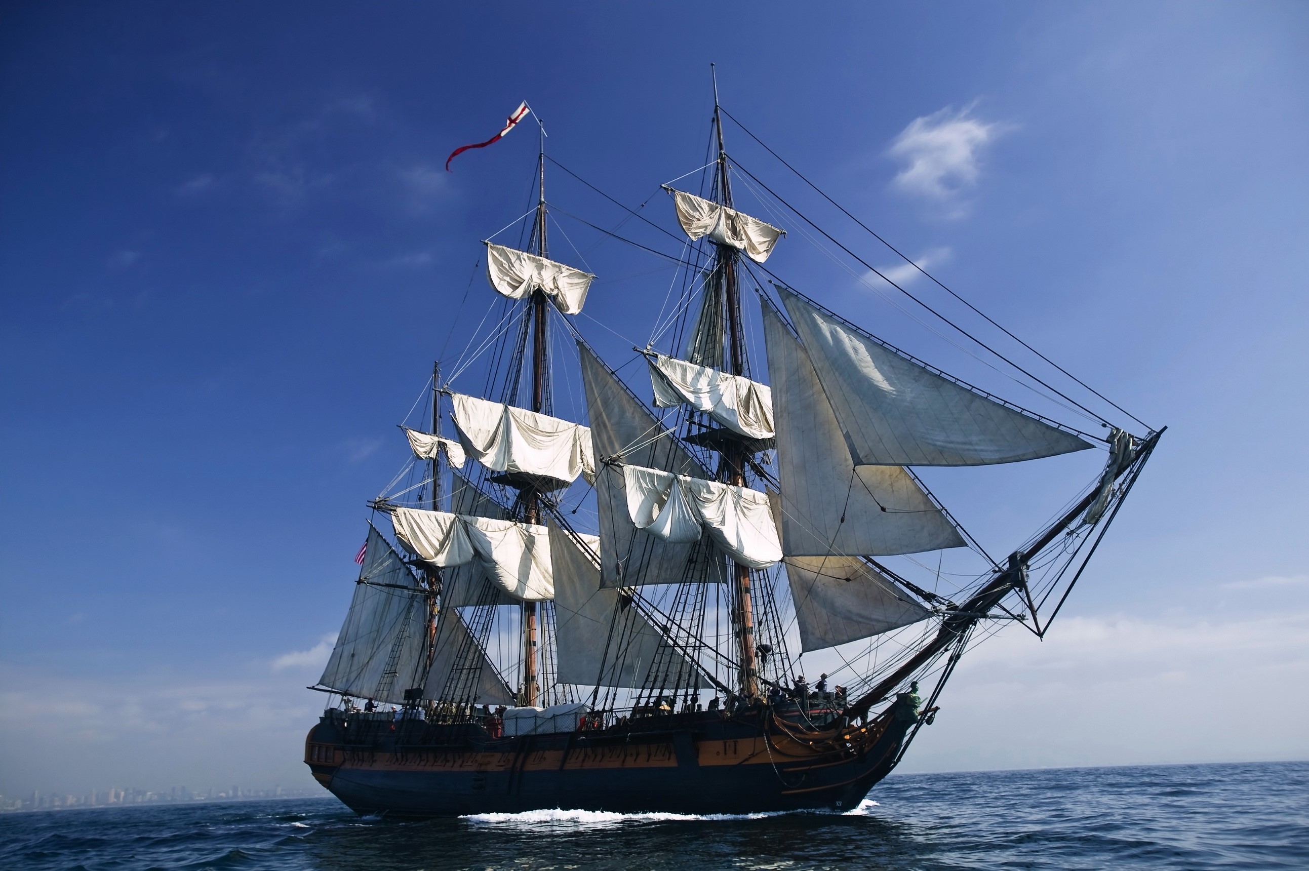 A tall sailing ship with white sails on the ocean HD Wallpaper