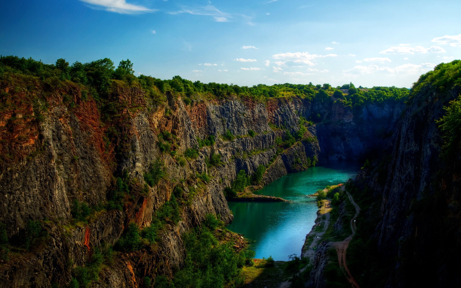 Quarry lake with steep rocky cliffs and trees HD Wallpaper