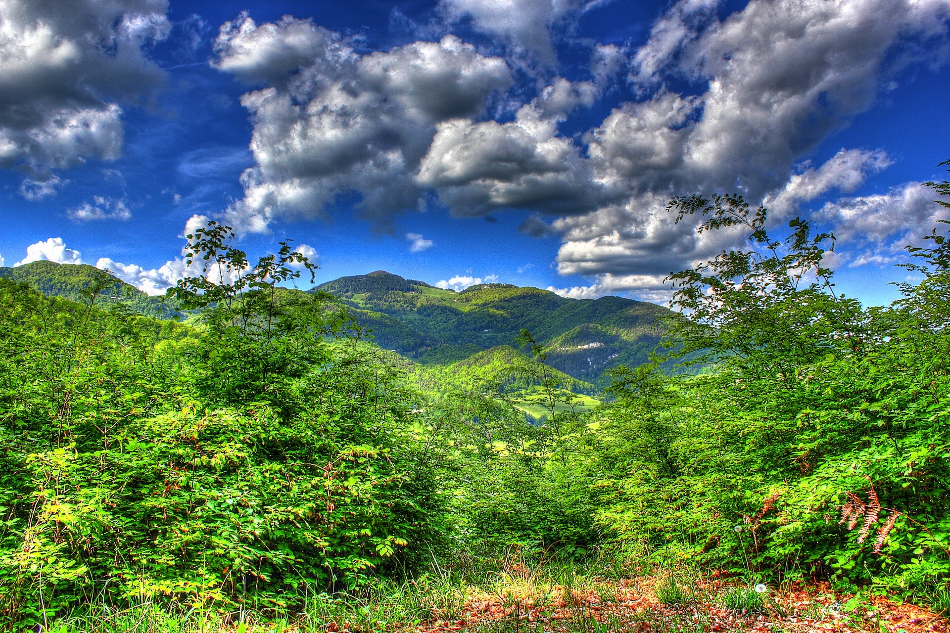 Green mountains under a cloudy blue sky HD Wallpaper