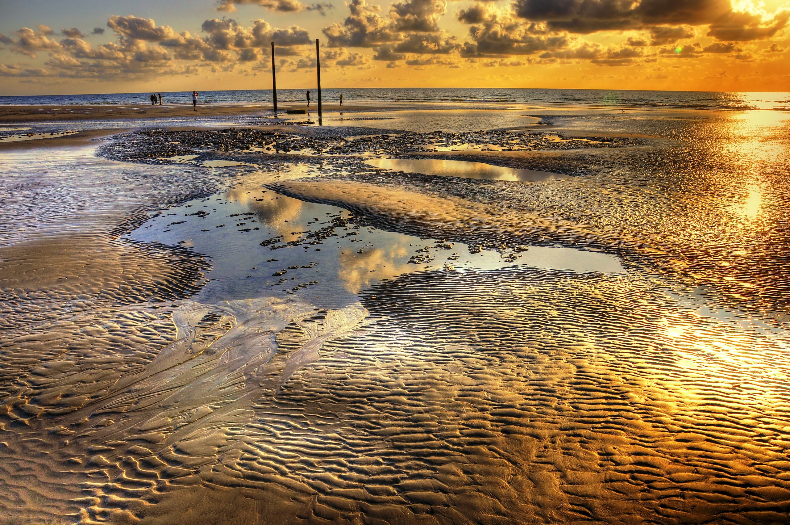 Beach at sunset with sand ripples and puddles HD Wallpaper