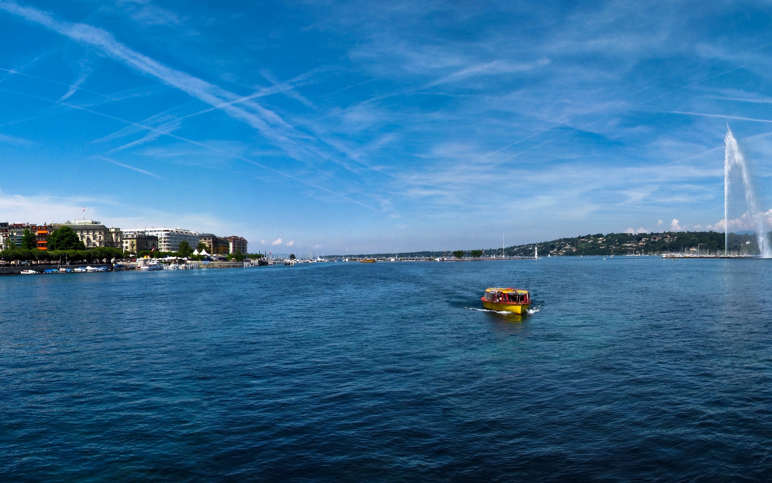 Yellow boat on a lake with a city and fountain HD Wallpaper