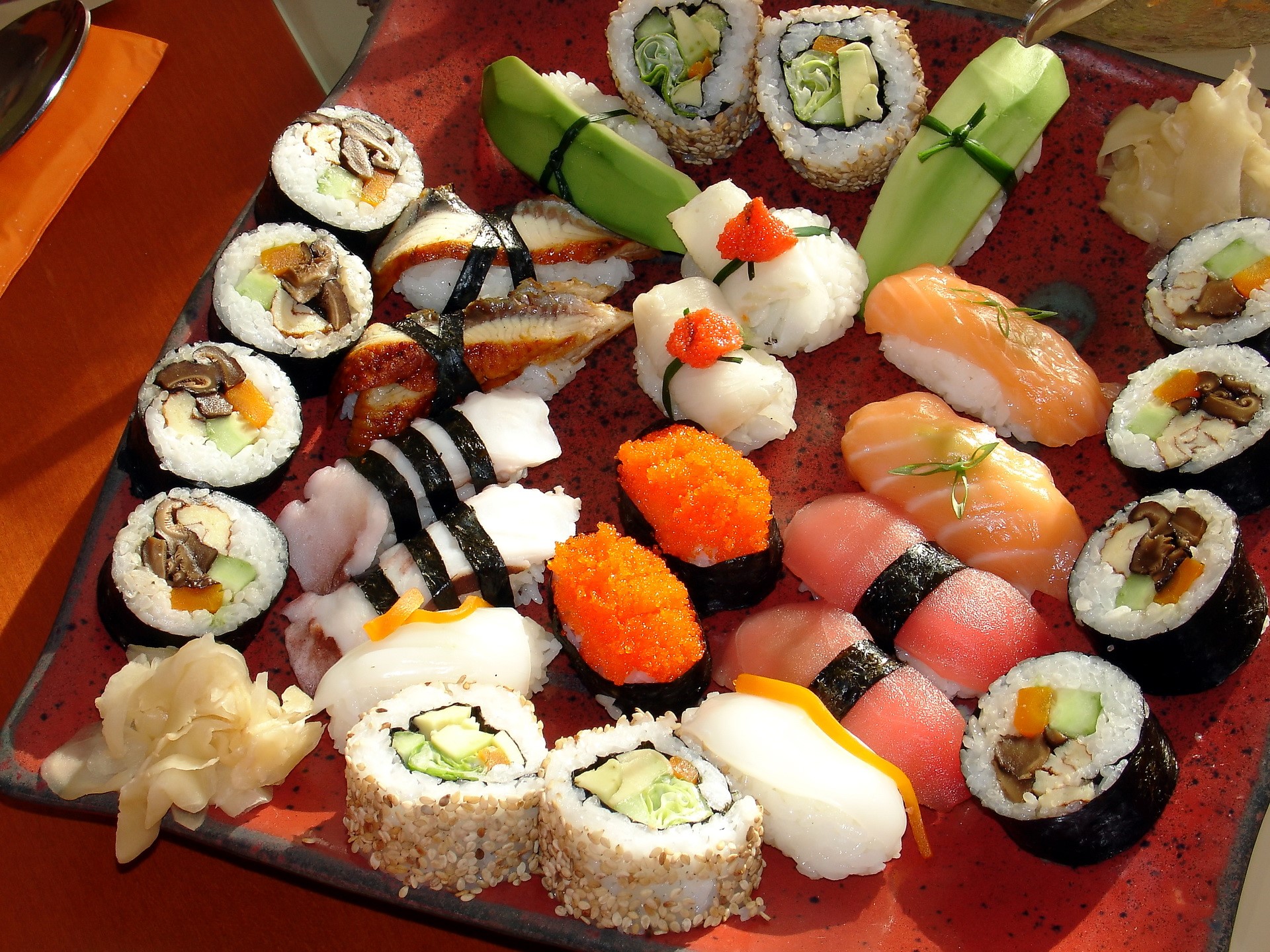 Assortment of sushi and sashimi on a red platter HD Wallpaper