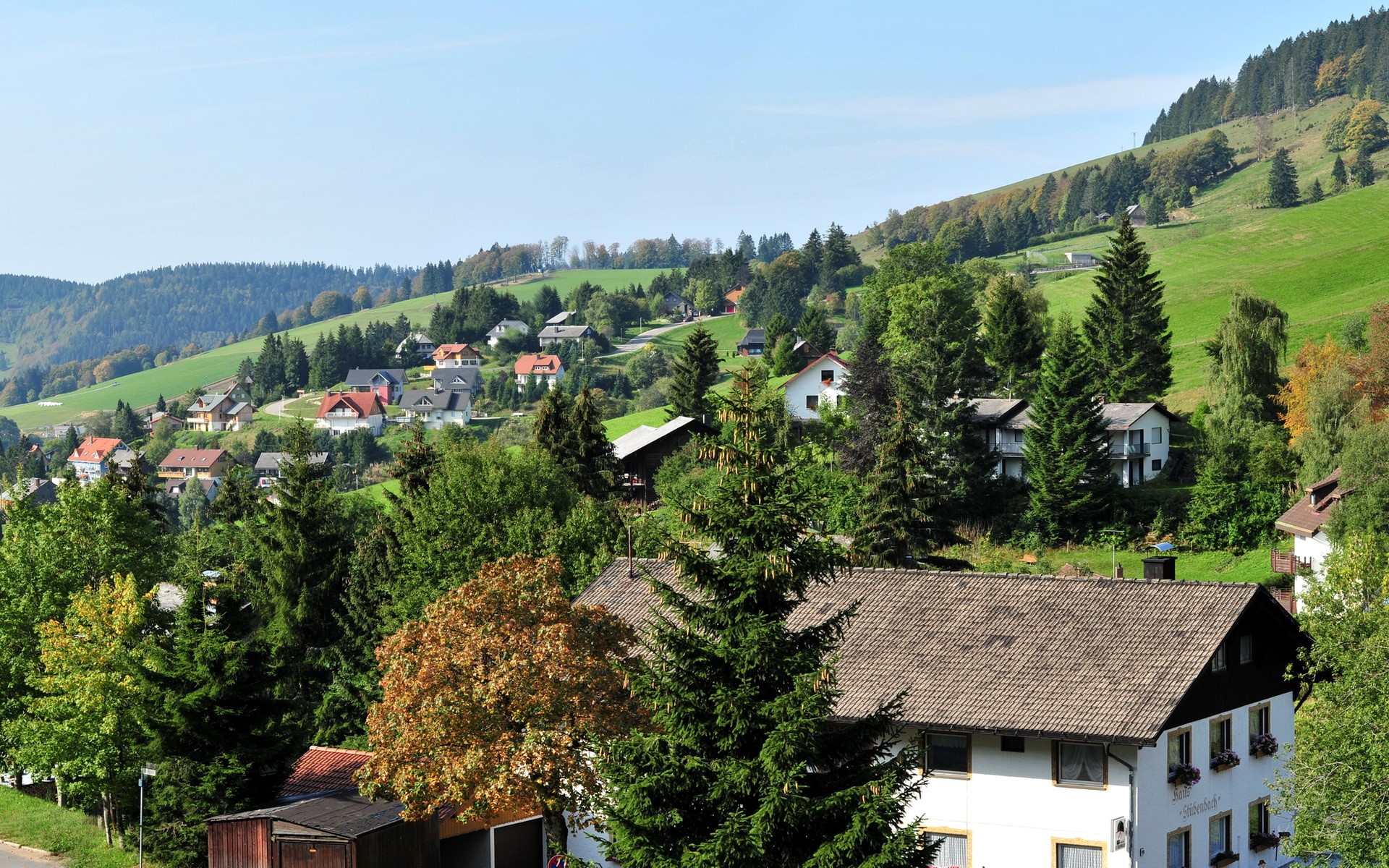 Village nestled in a green, hilly landscape in Germany HD Wallpaper