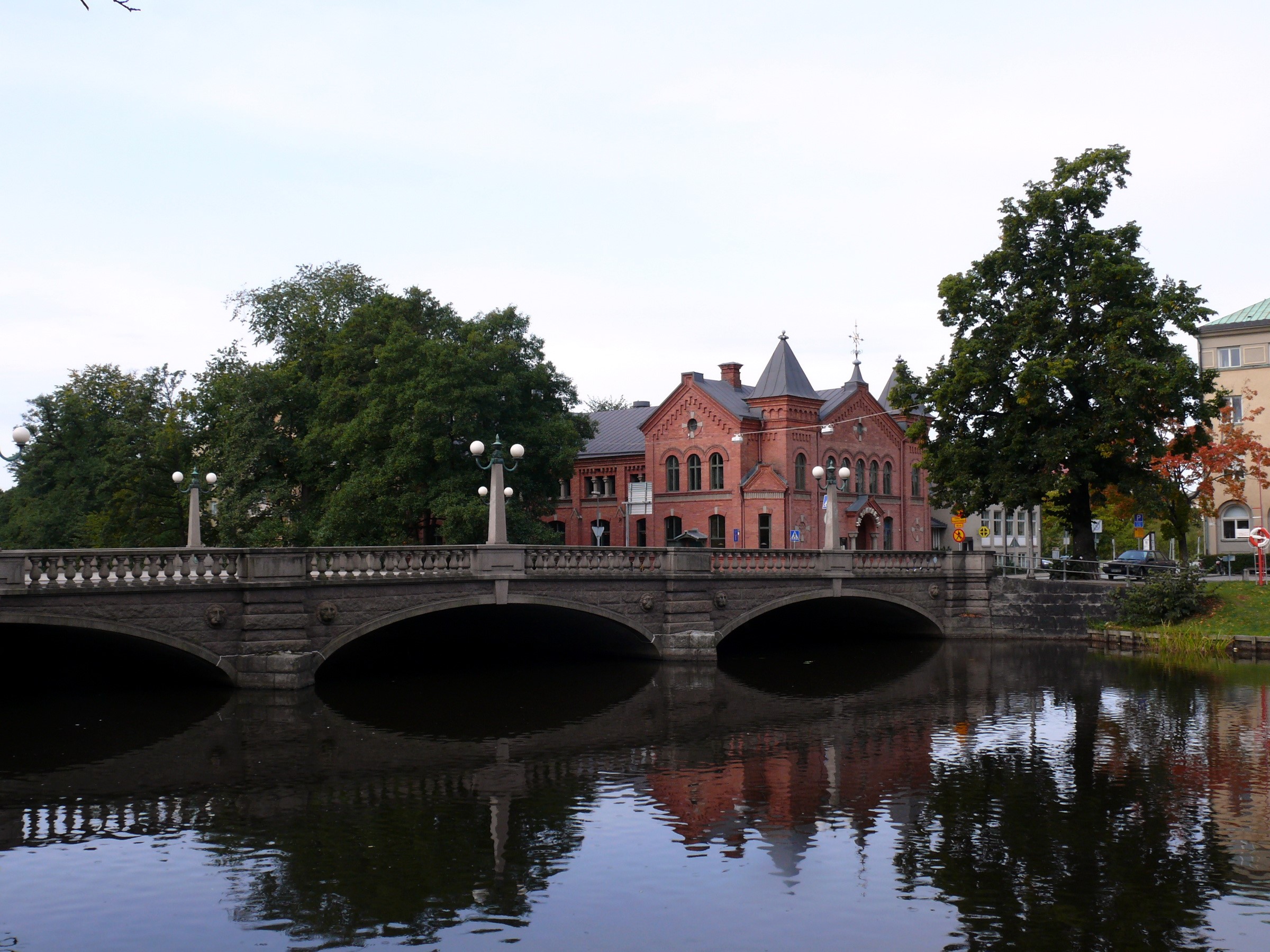 Stone bridge over a canal with a brick building in Sweden HD Wallpaper