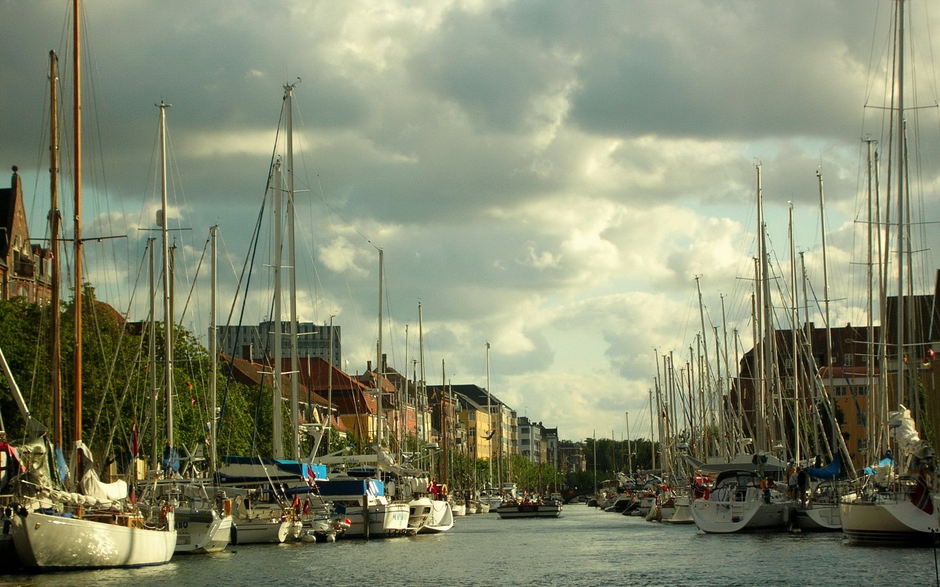Sailboats docked in a canal with buildings in the background HD Wallpaper