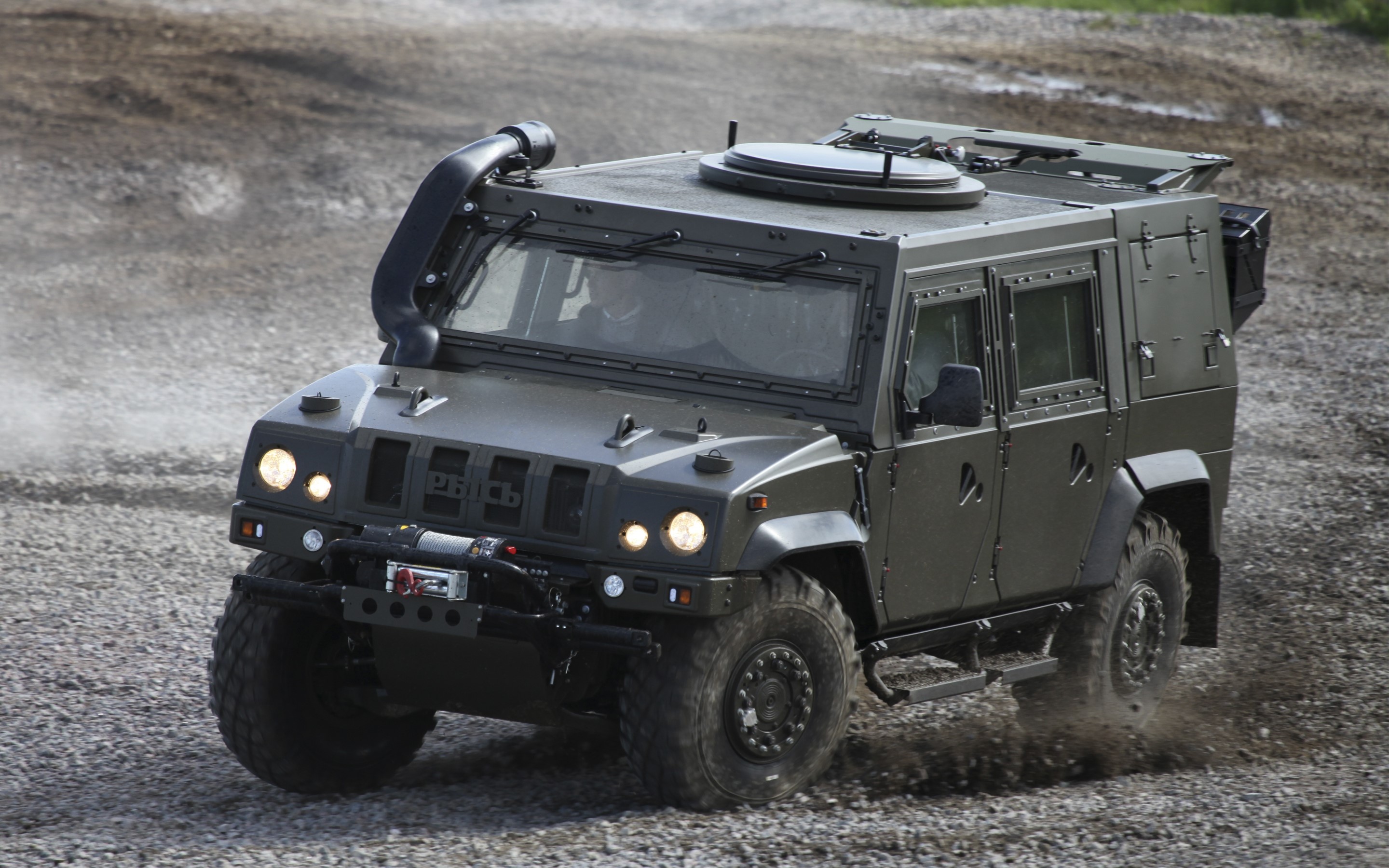 Military armored vehicle driving on gravel HD Wallpaper