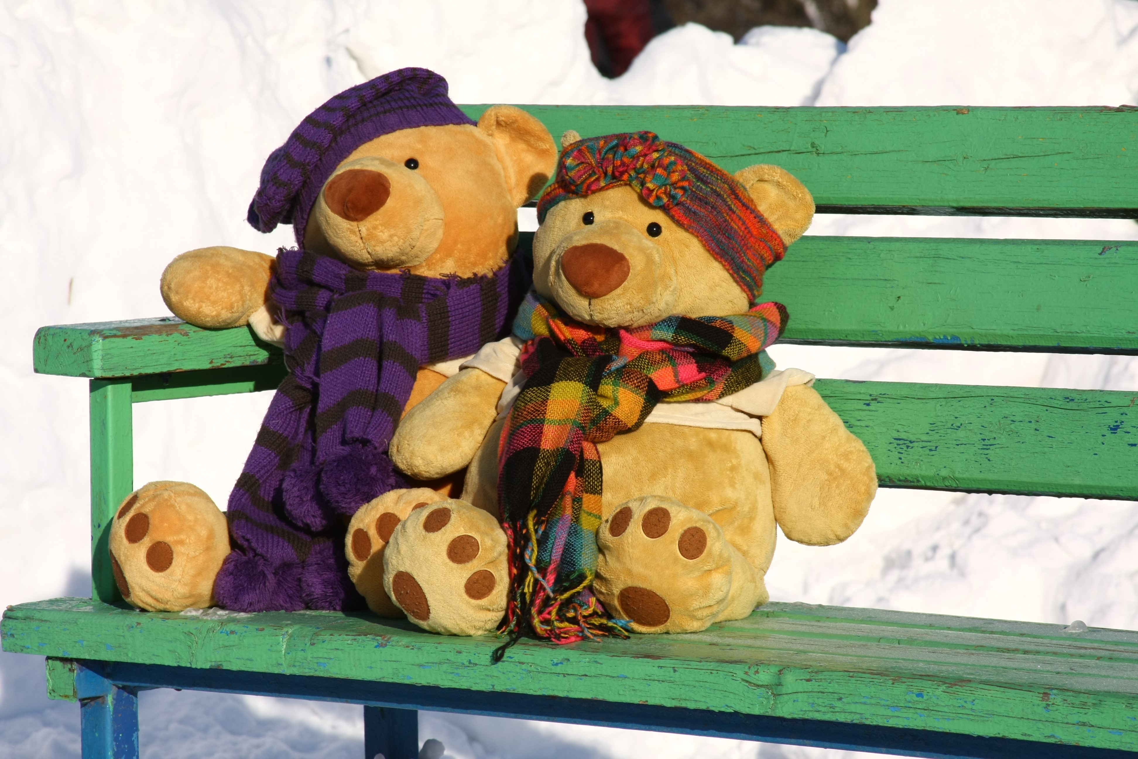 Two teddy bears sitting on a bench in the snow HD Wallpaper