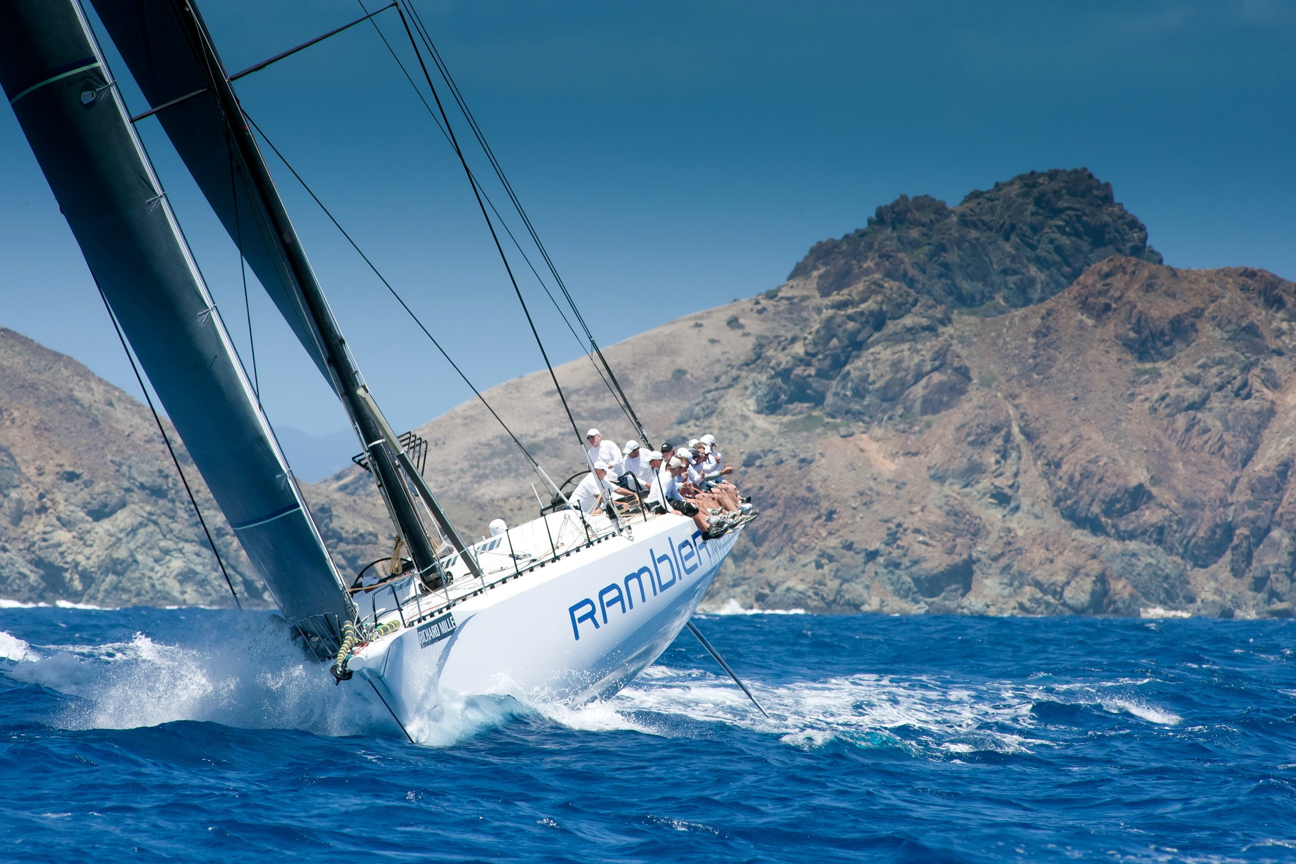 Rambler yacht sailing in the ocean near a rocky island HD Wallpaper