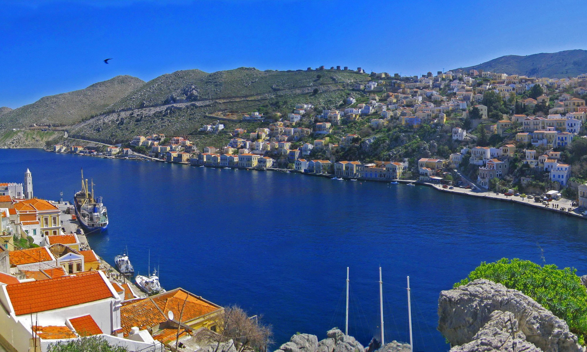 View of Ano Symi, Greece with harbor and colorful houses HD Wallpaper
