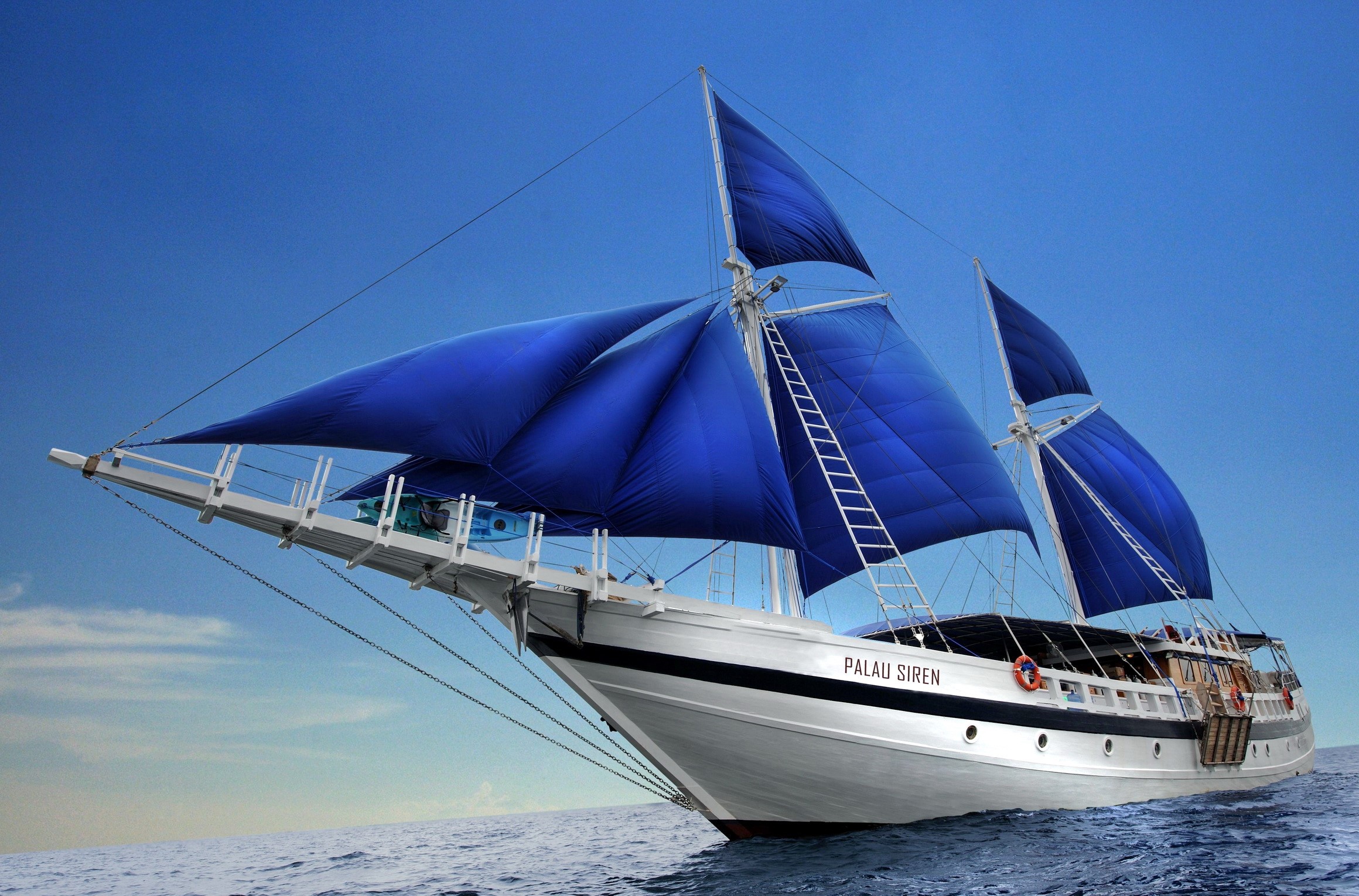 Palau Siren sailboat with blue sails on the ocean HD Wallpaper