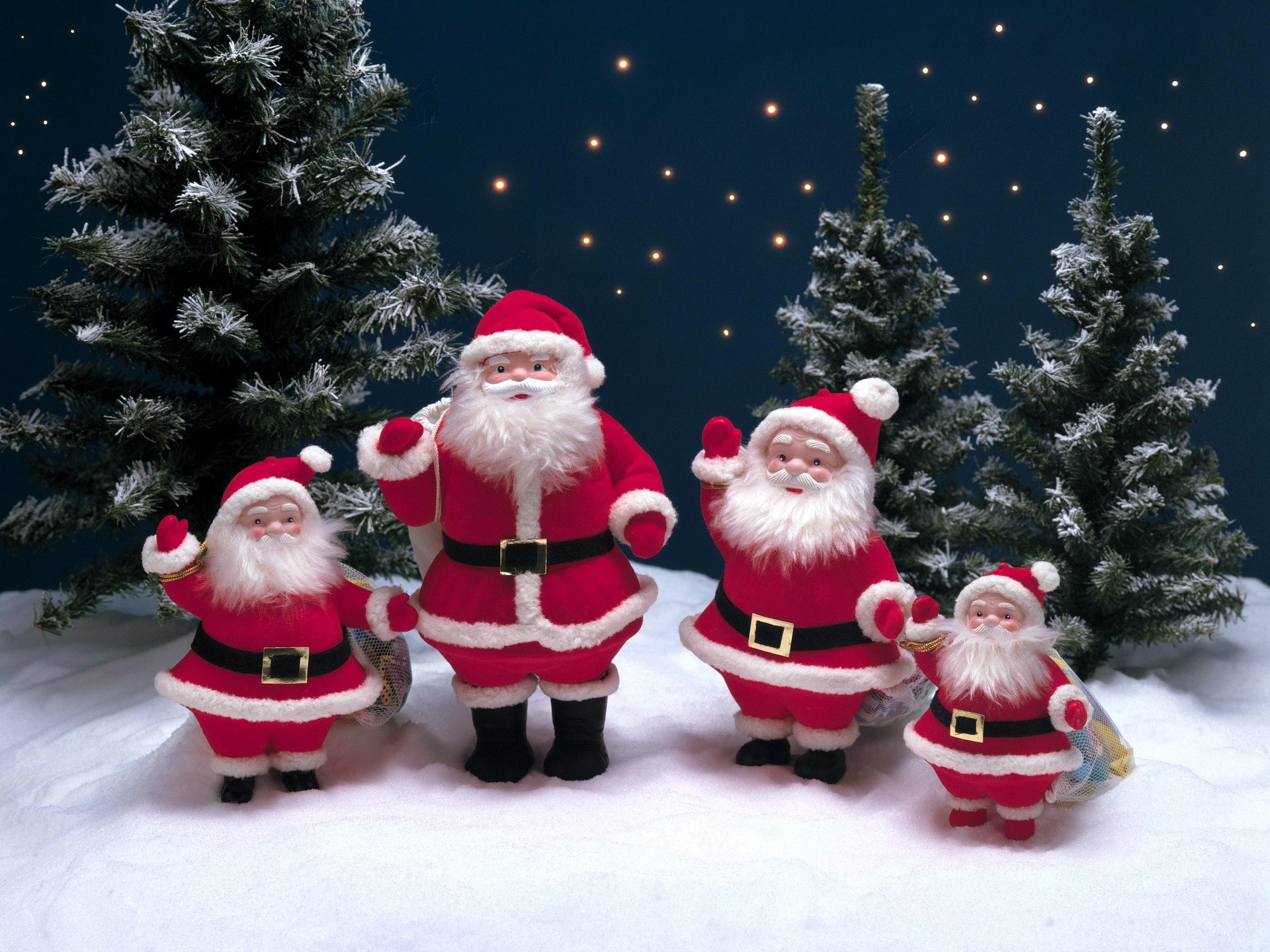 Four Santa Claus figures in a snowy forest setting HD Wallpaper