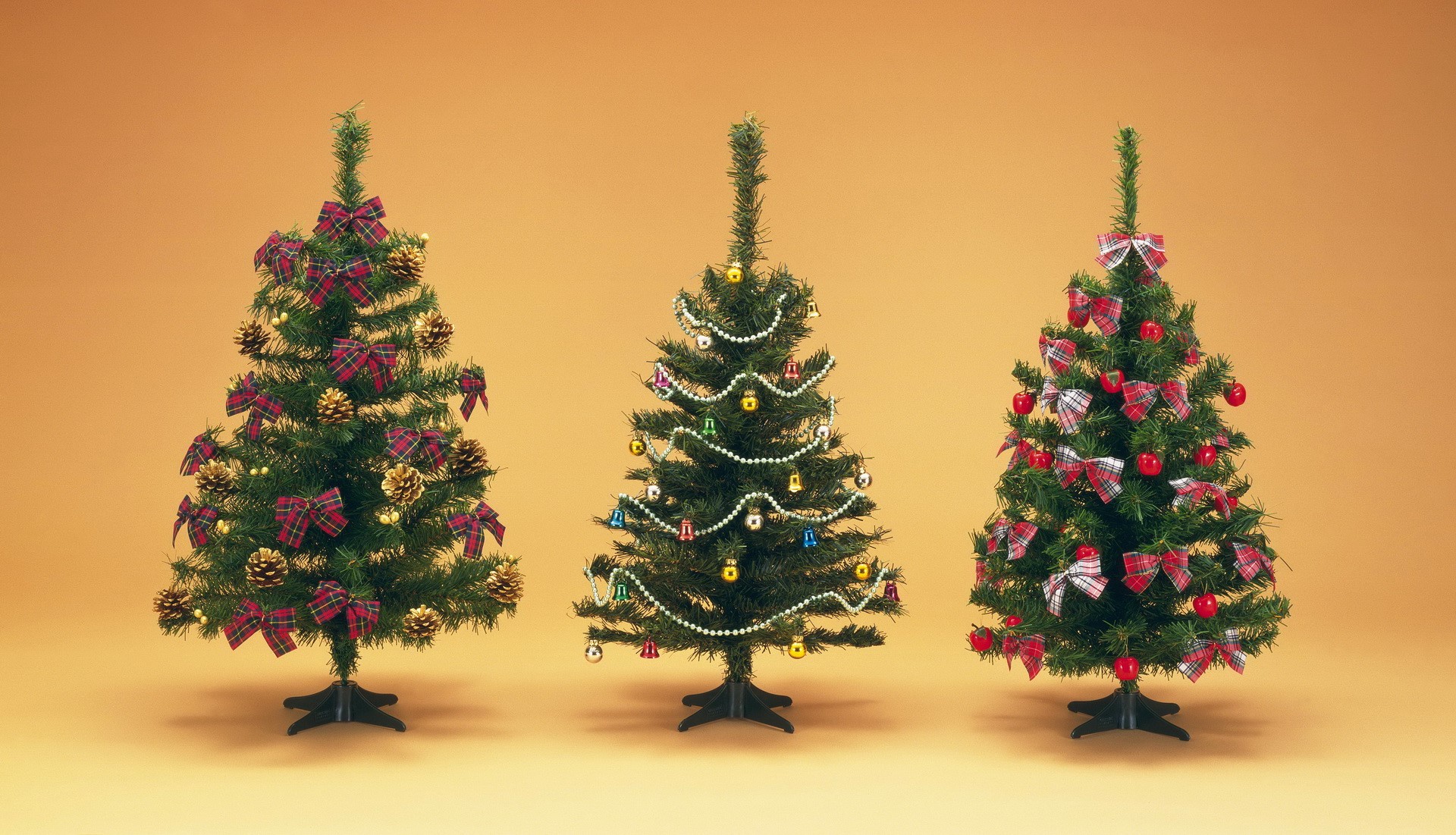 Three decorated Christmas trees on an orange background HD Wallpaper