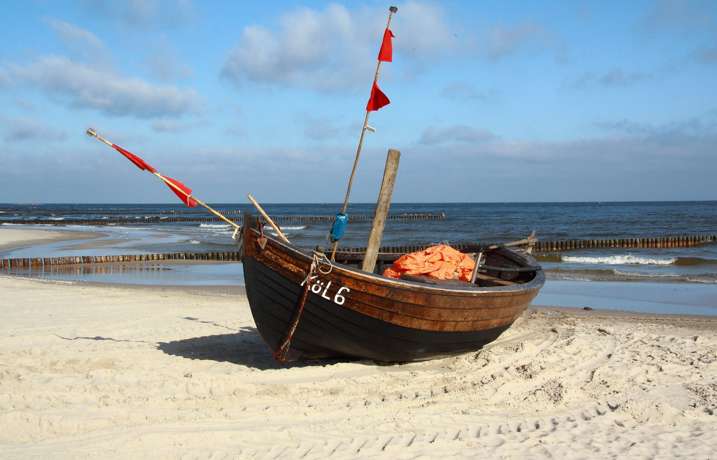 Fishing boat on a sandy beach with red flags HD Wallpaper