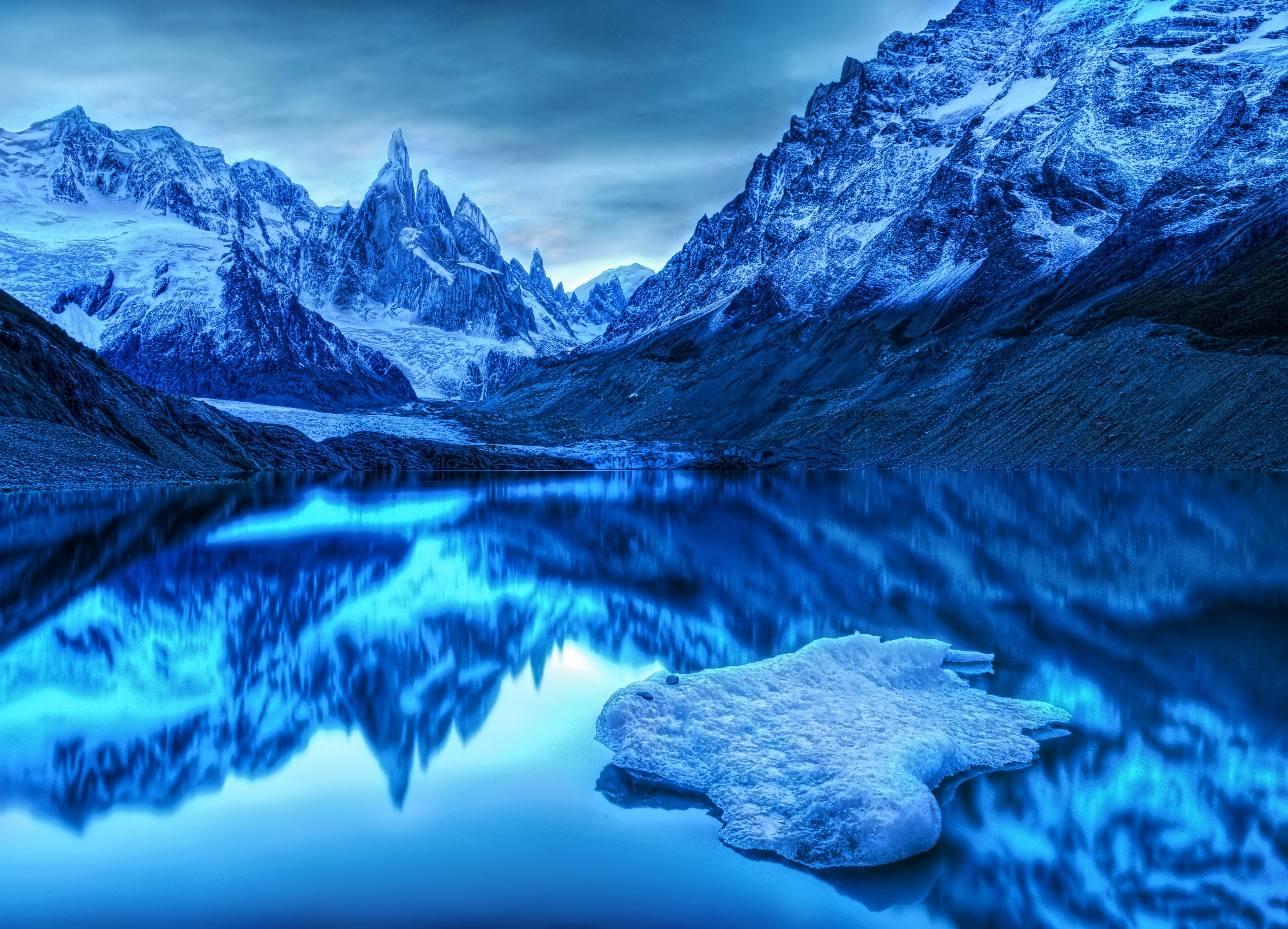 Snow-capped mountains reflected in a lake with ice floe HD Wallpaper